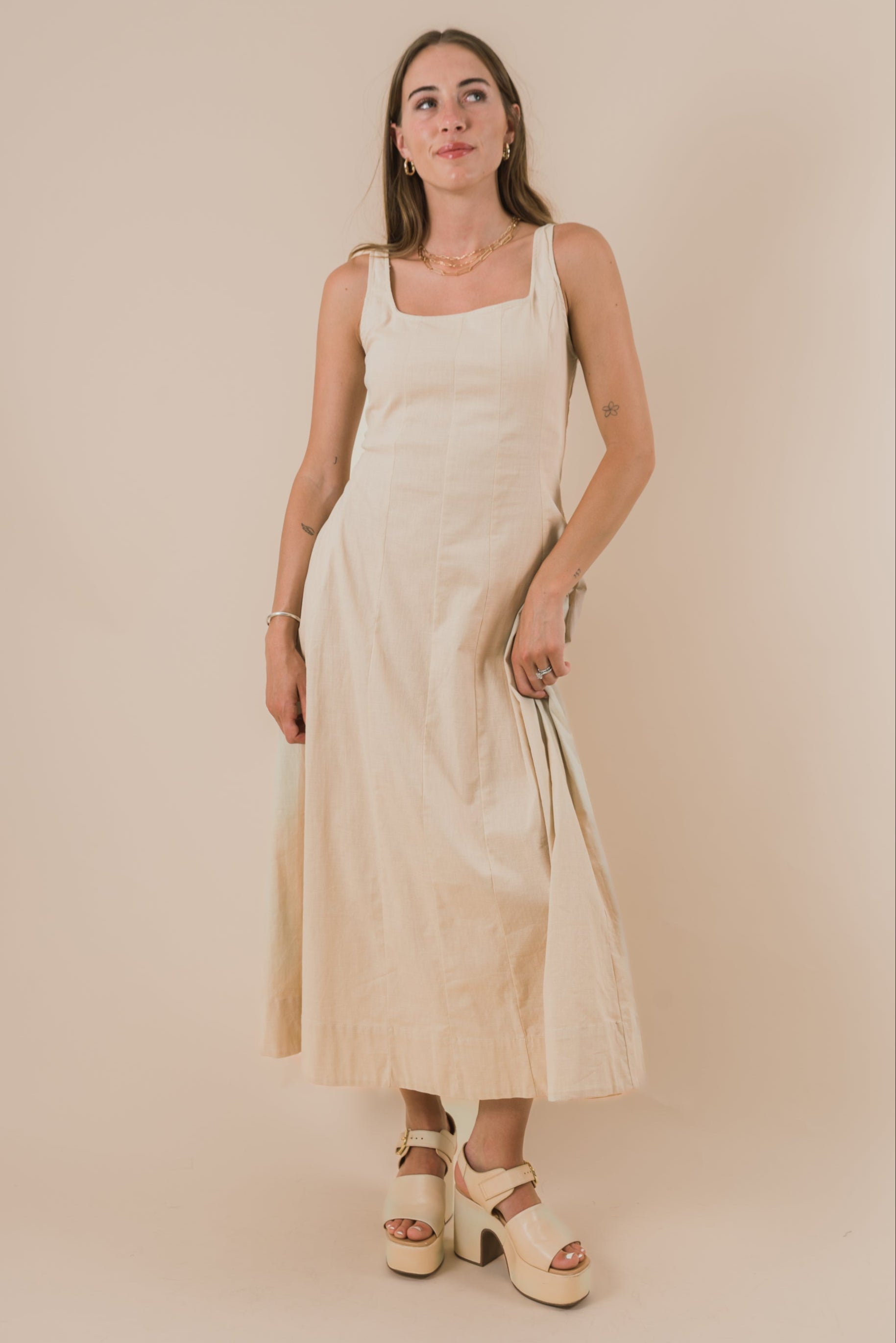 Woman wearing a beige dress against a plain background