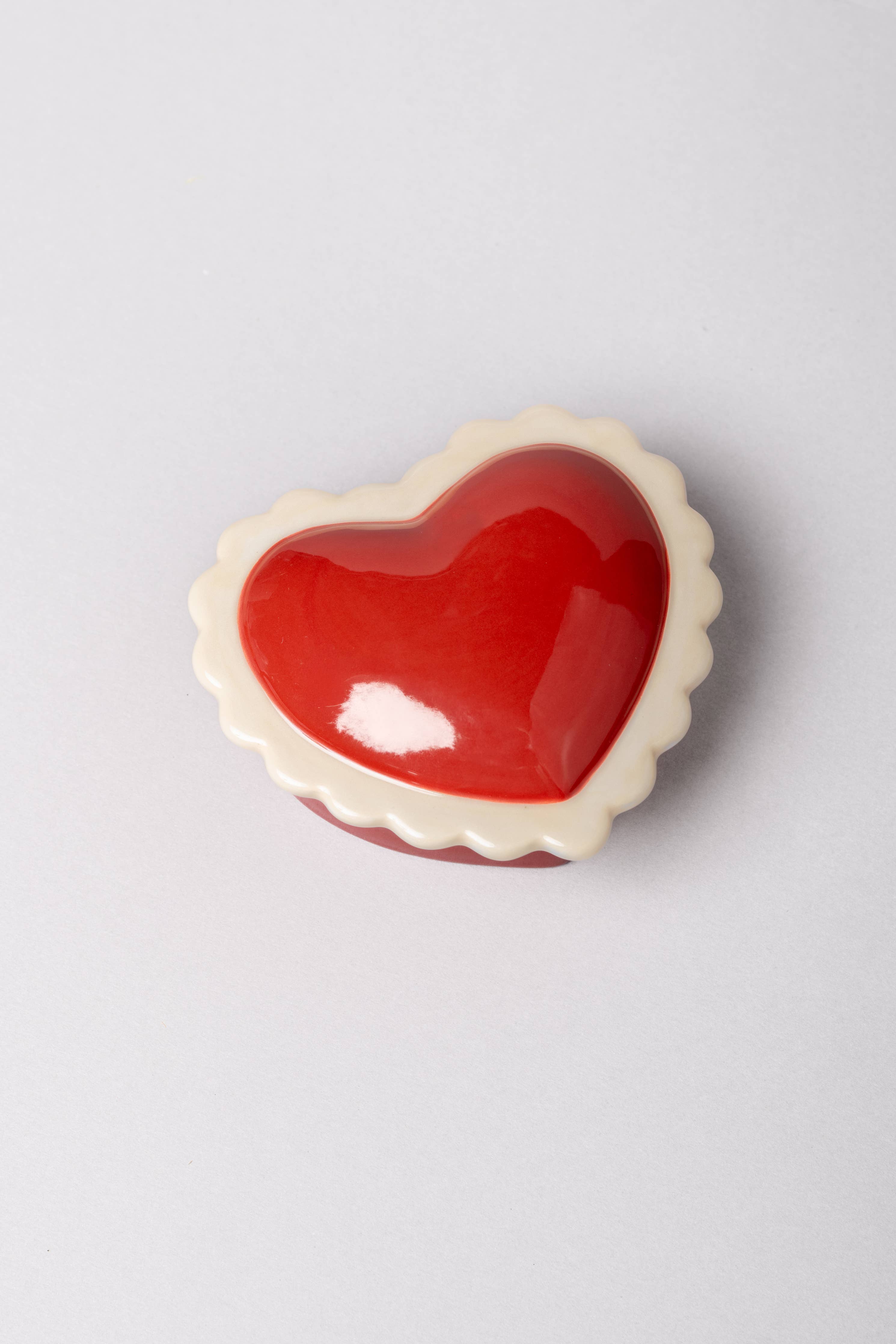 Heart-shaped red object on a light gray background trinket box with lid