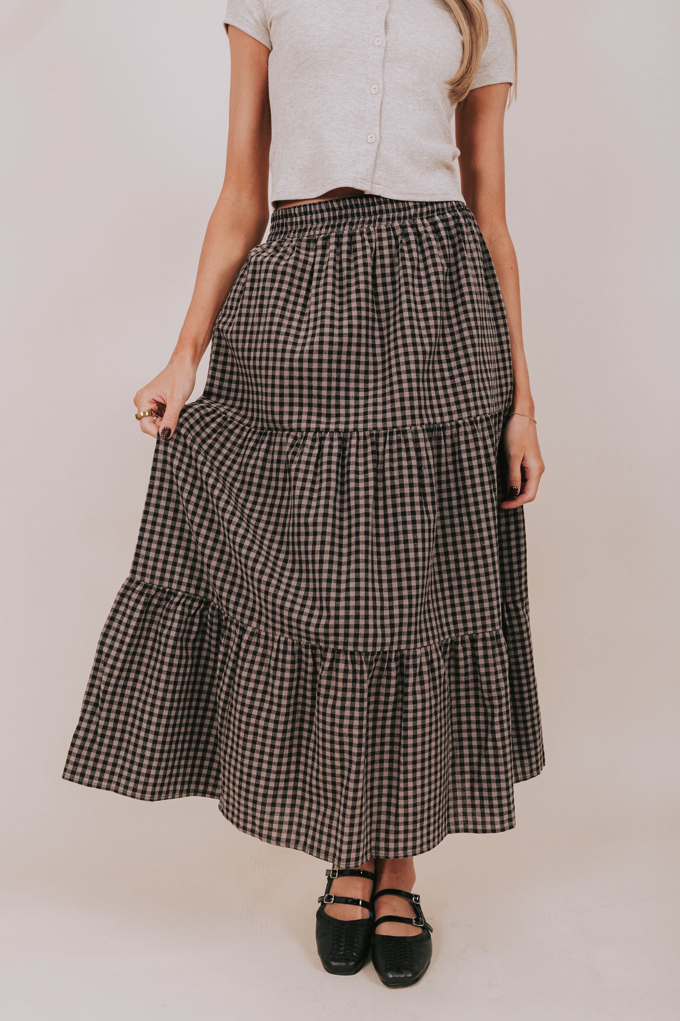 Person wearing a checkered tiered skirt on a plain background