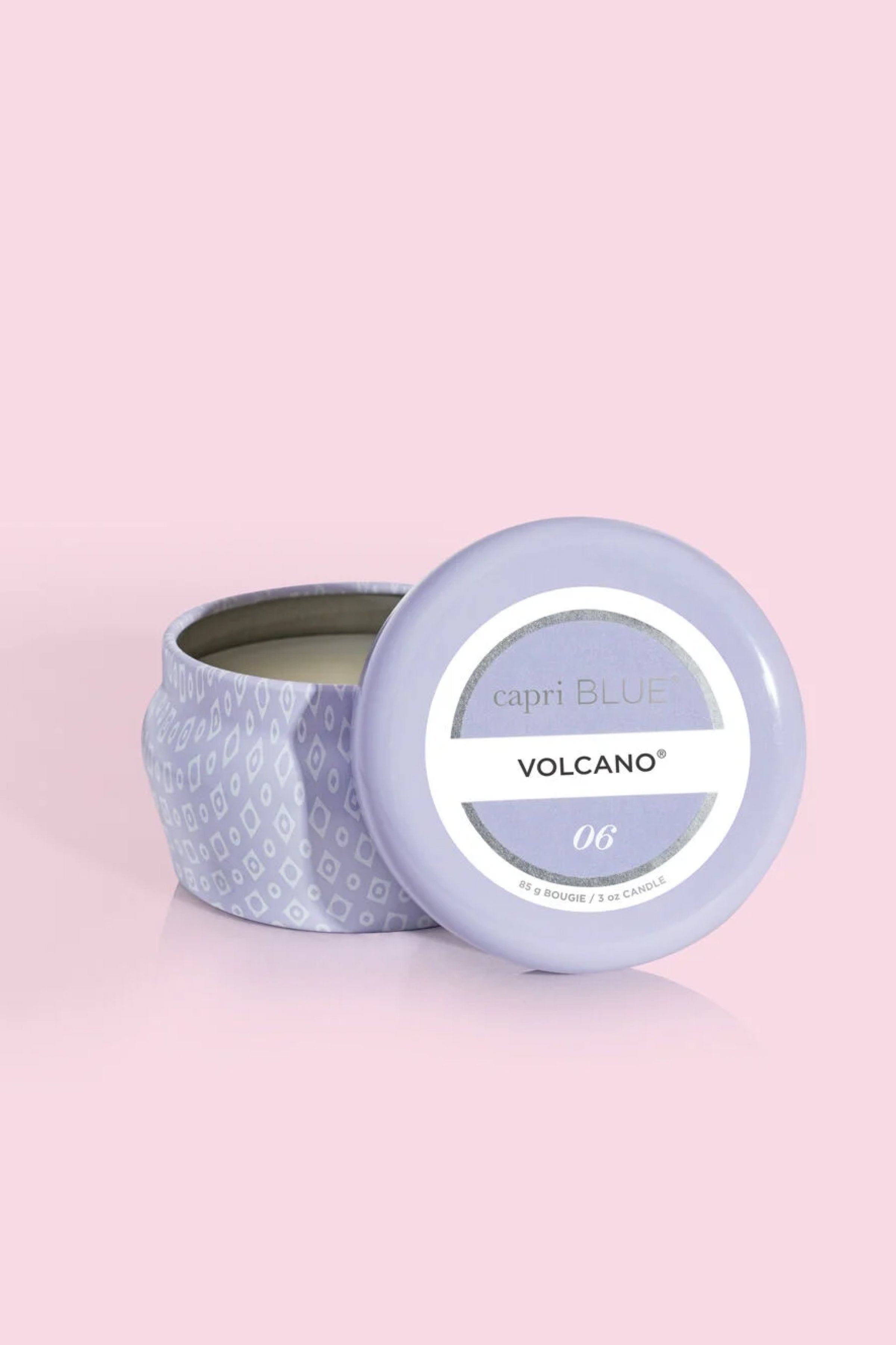 Candle in a decorative tin with 'Volcano' label on a pink background