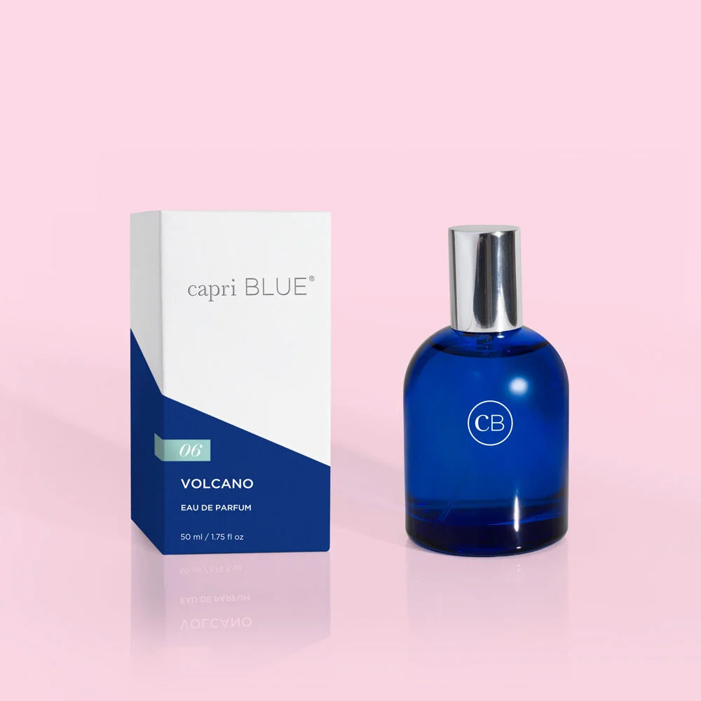 Blue perfume bottle with silver cap and 'capri BLUE' packaging on a pink background