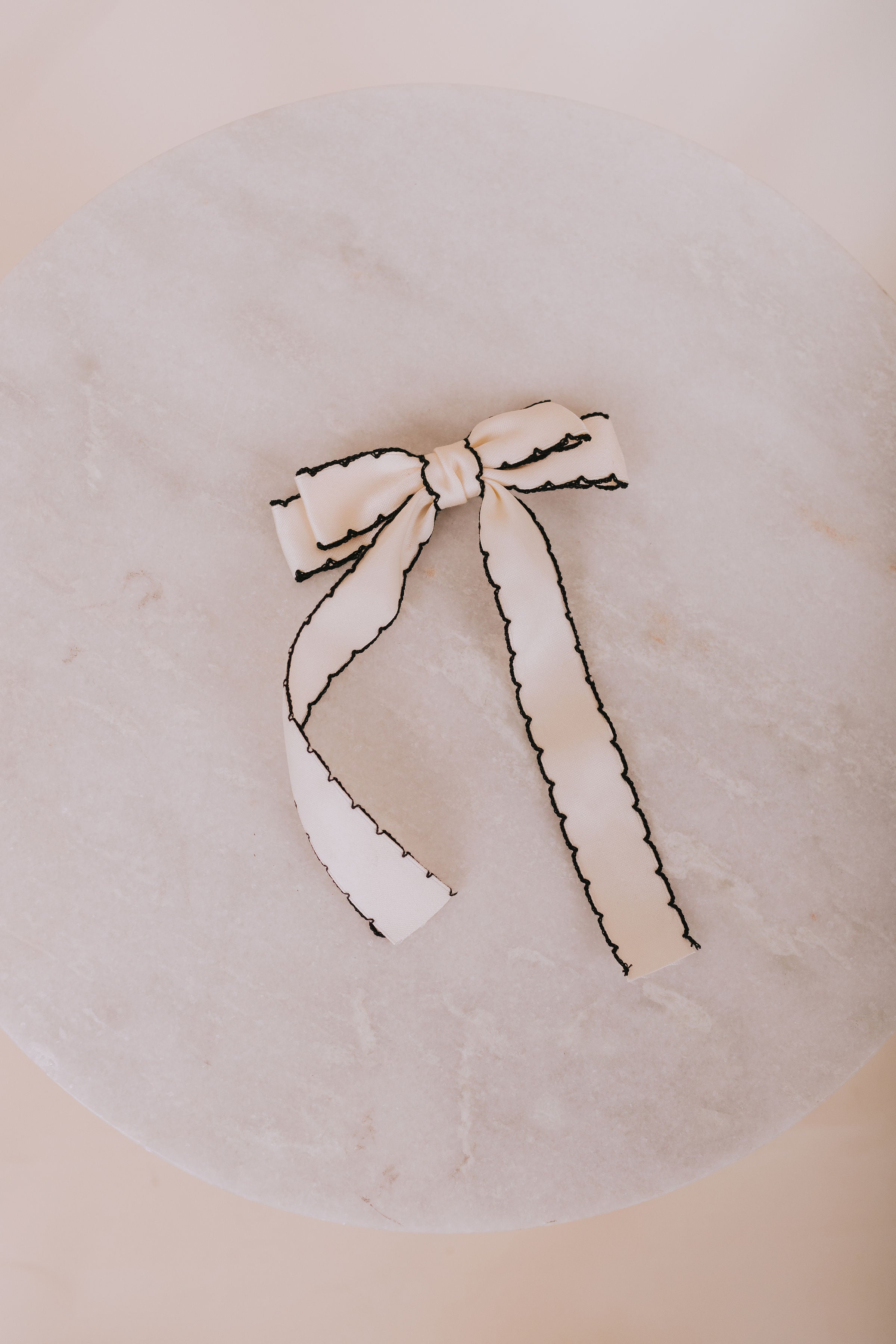 White bow with black trim on a round beige surface