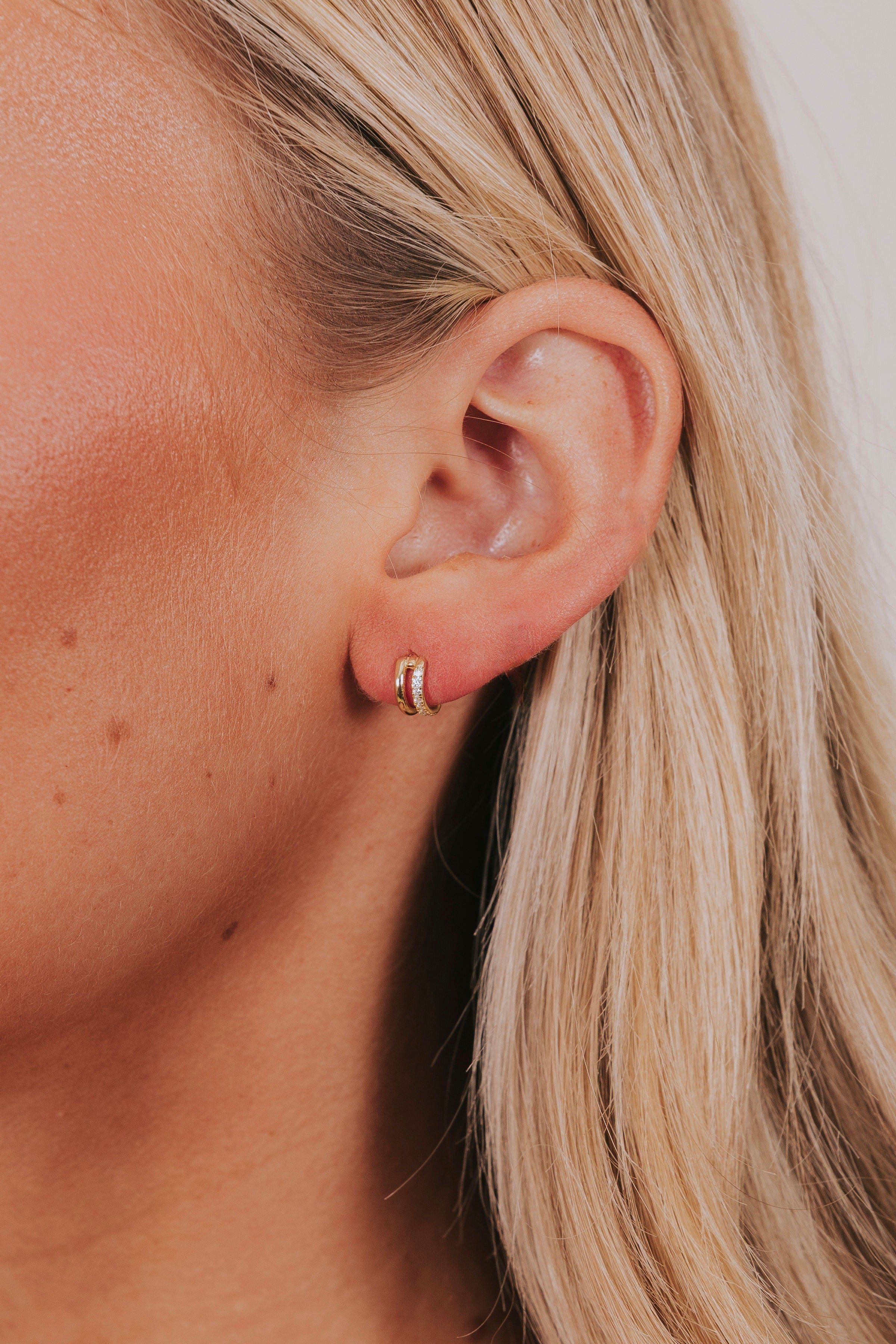 pair of gold colored 925 sterling silver earrings with a double hoop design with rhinestone accent.