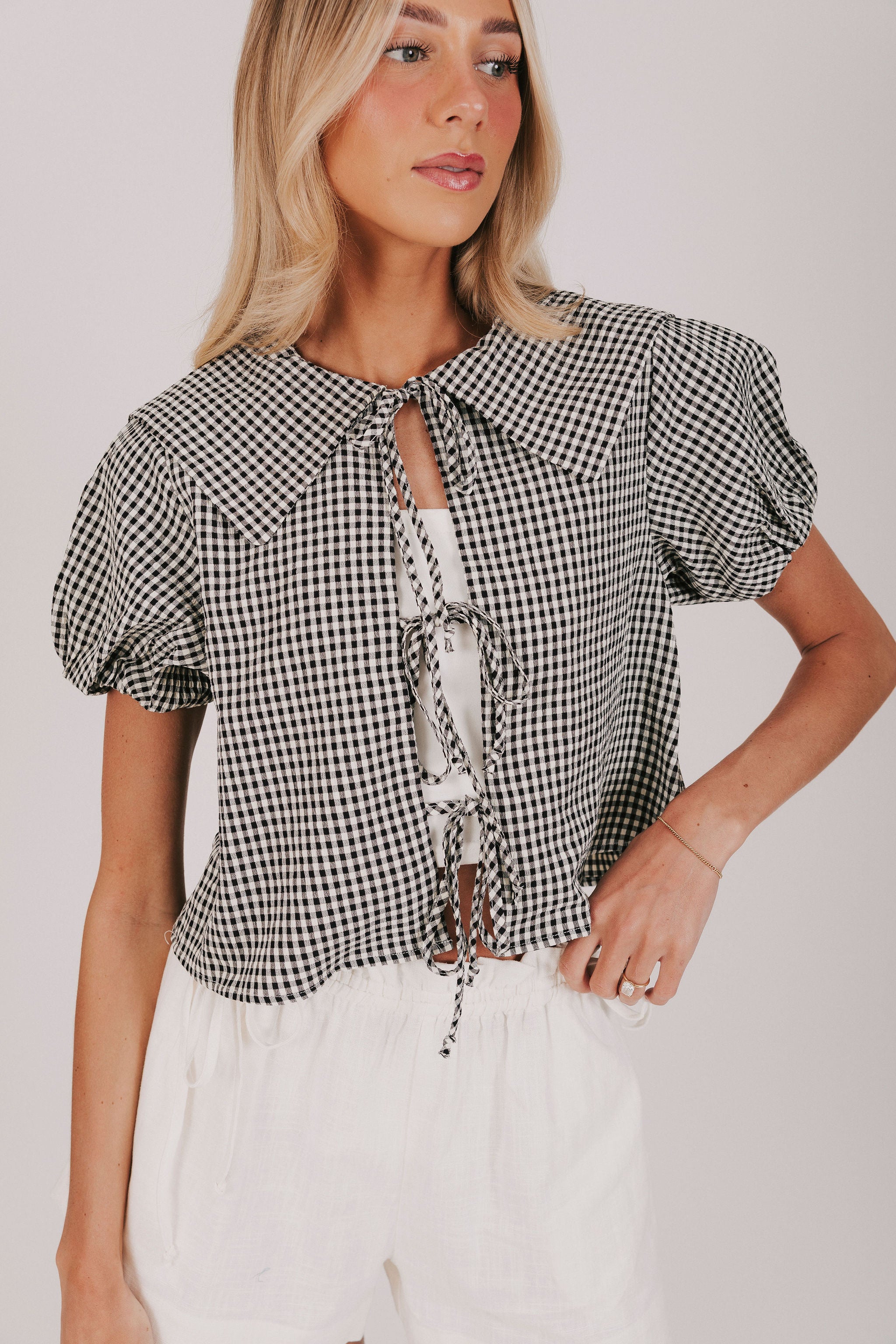 gingham blouse with open front and tied bow closure. Short puff sleeves