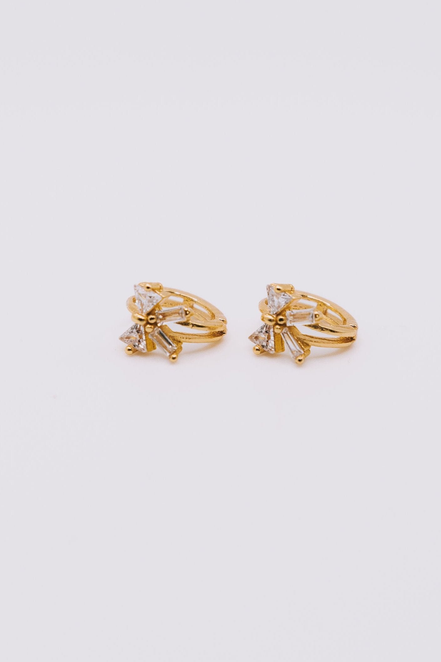 Pair of gold earrings with small diamonds on a light gray background