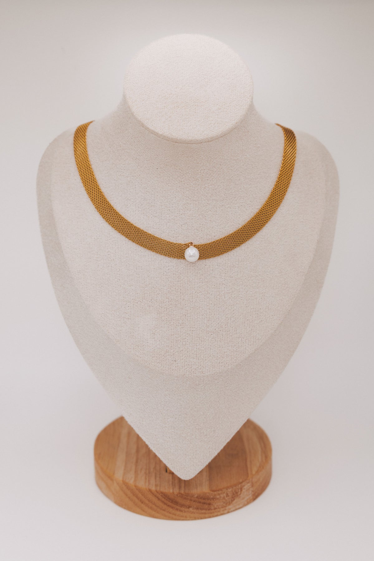Necklace with a pearl pendant on a mannequin bust against a white background