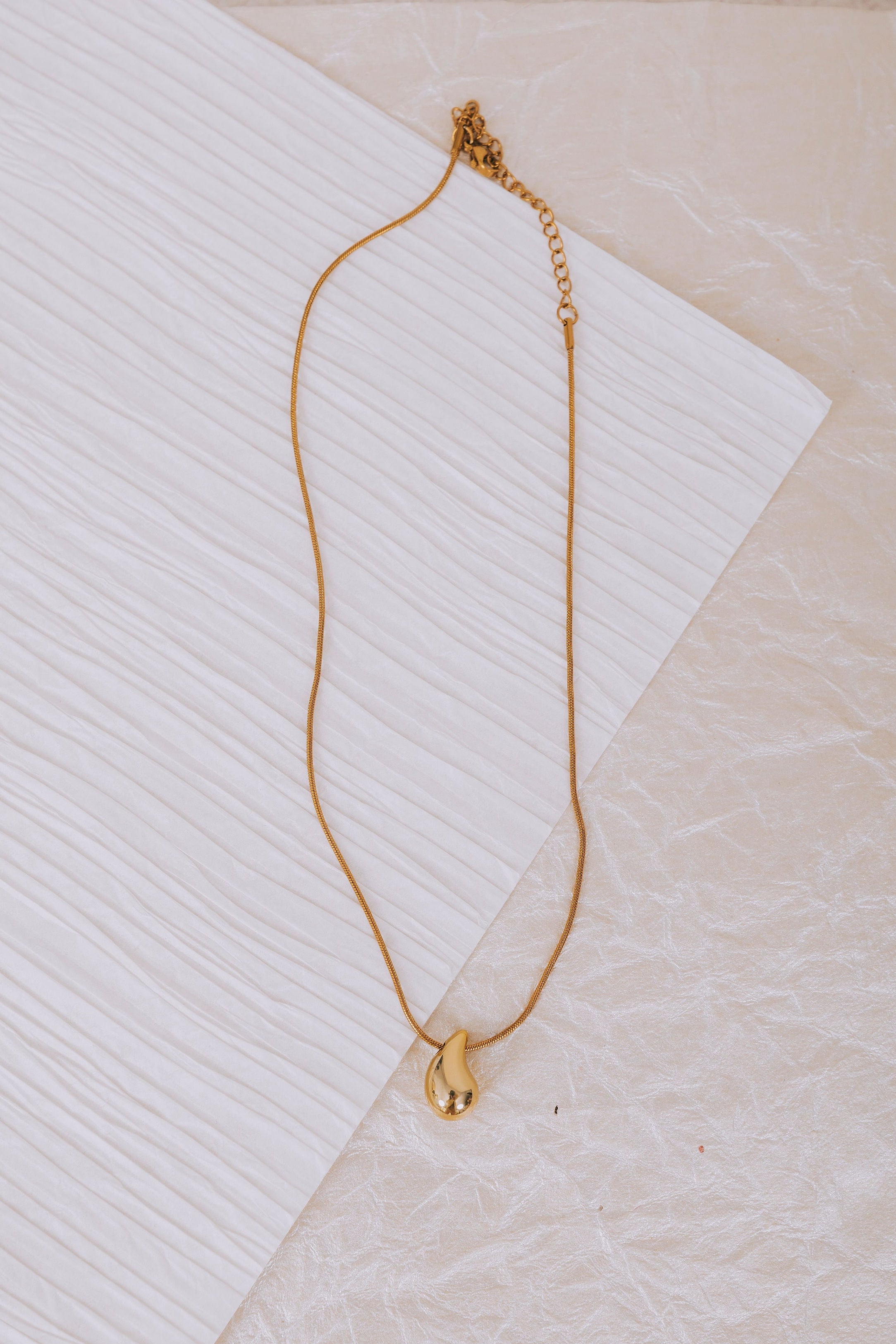 gold raindrop pendant necklace flatlay
