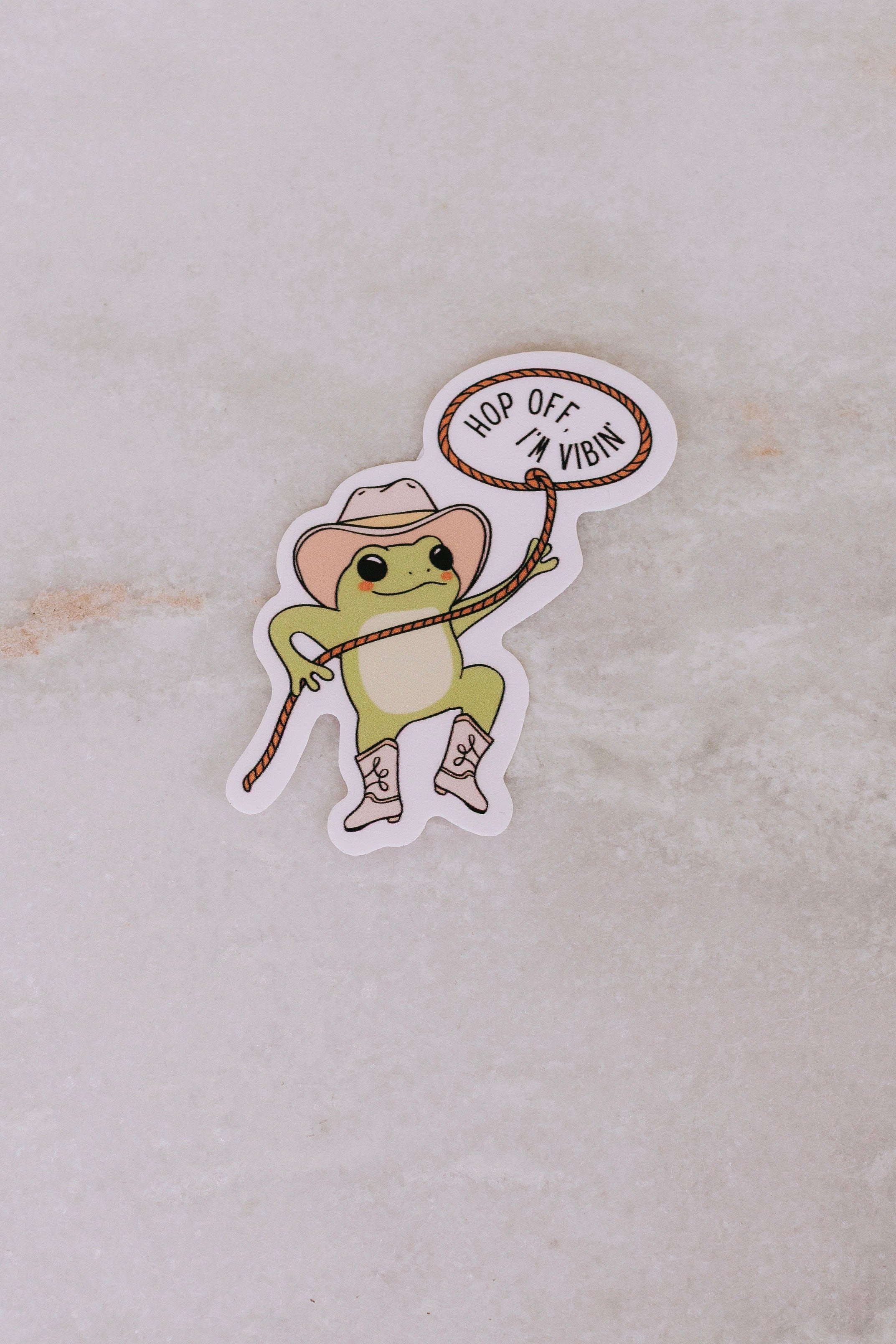 Sticker of a frog in a cowboy hat with text on a light background