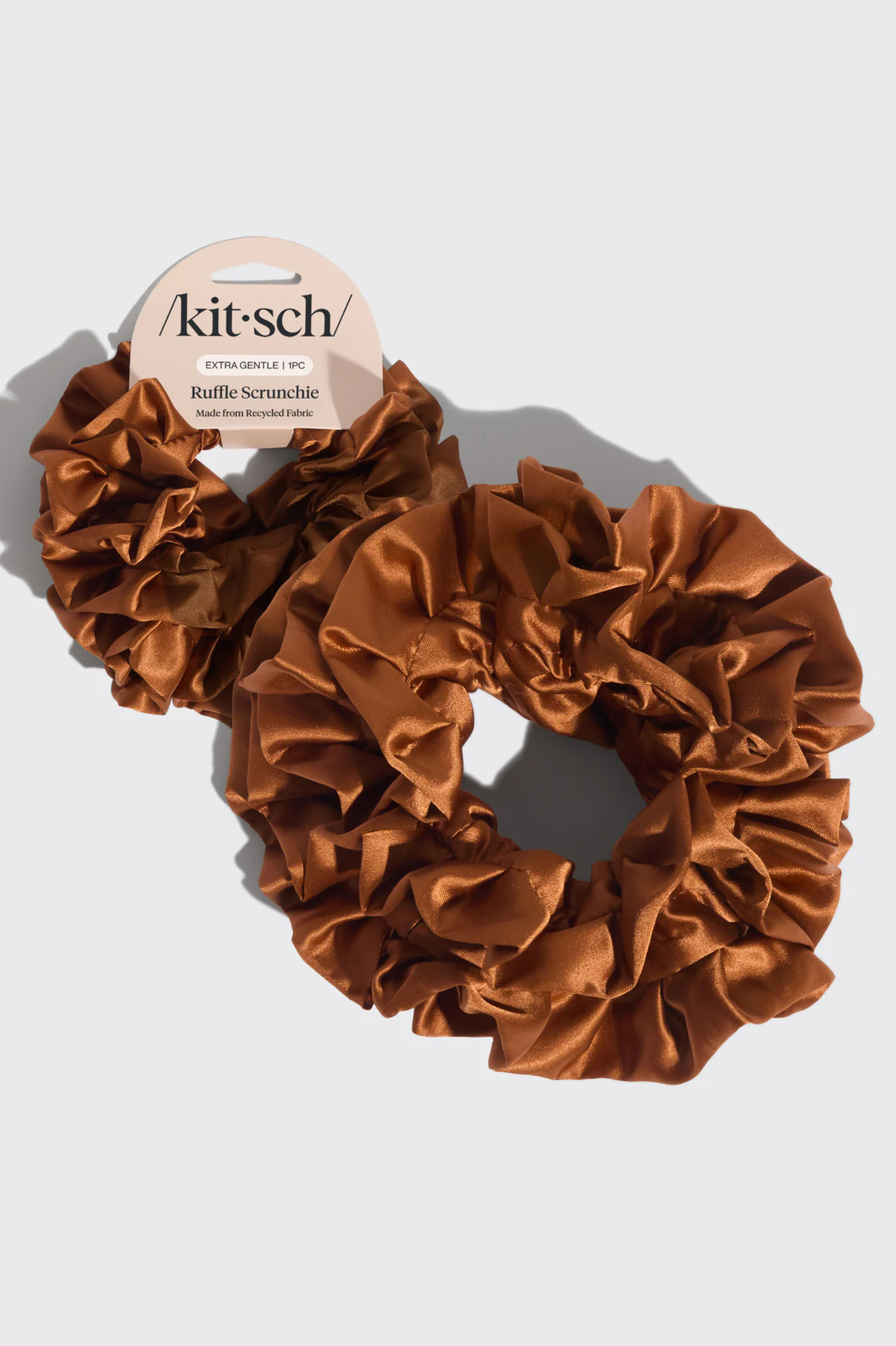 Brown scrunchie with 'kit-sch' branding on a light gray background