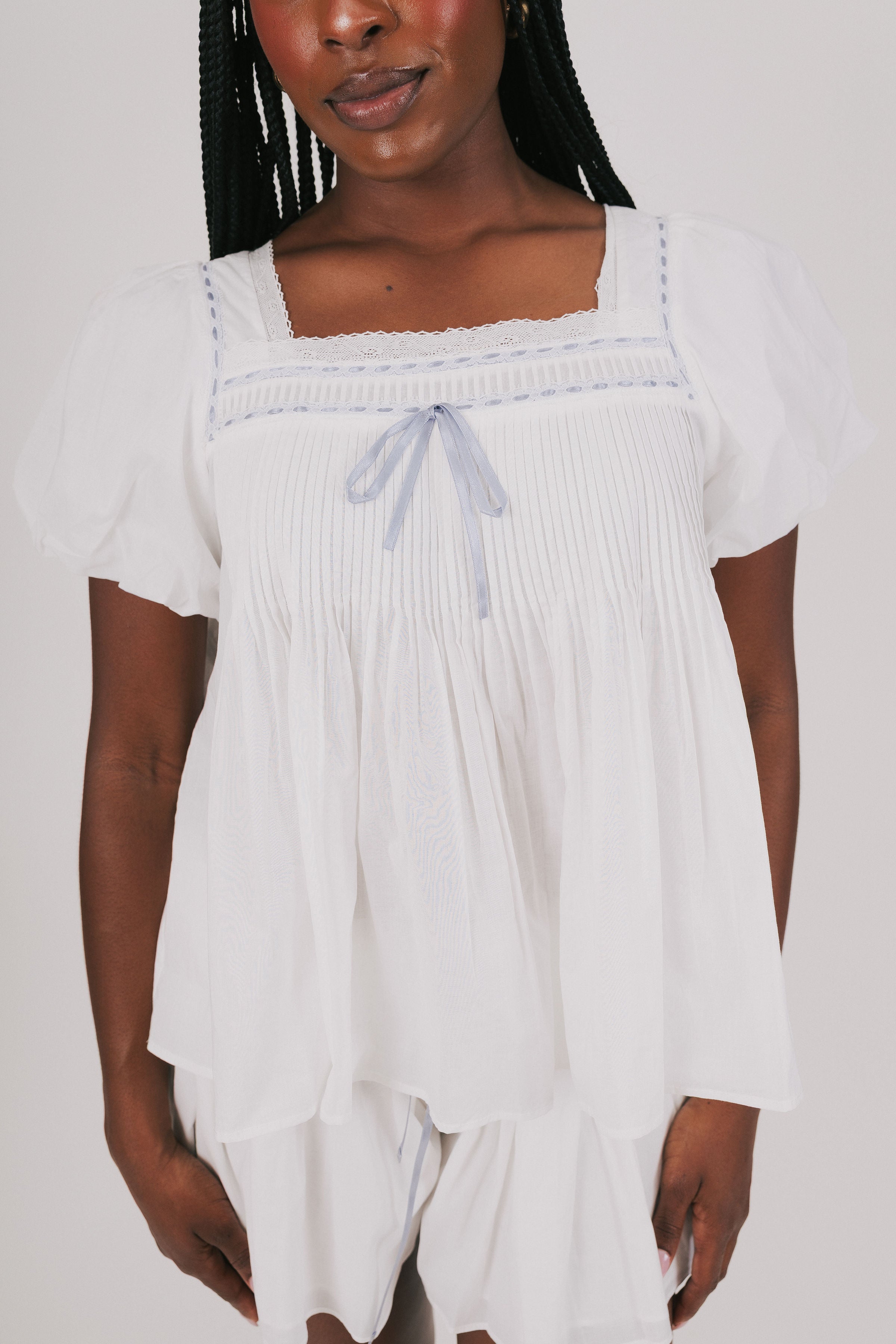 loose white top with blue ribbon detail and lace close