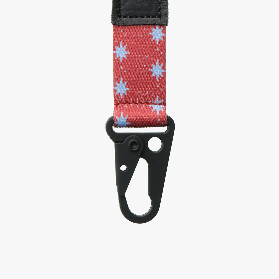 Keychain with red strap featuring blue star patterns and black carabiner by thread