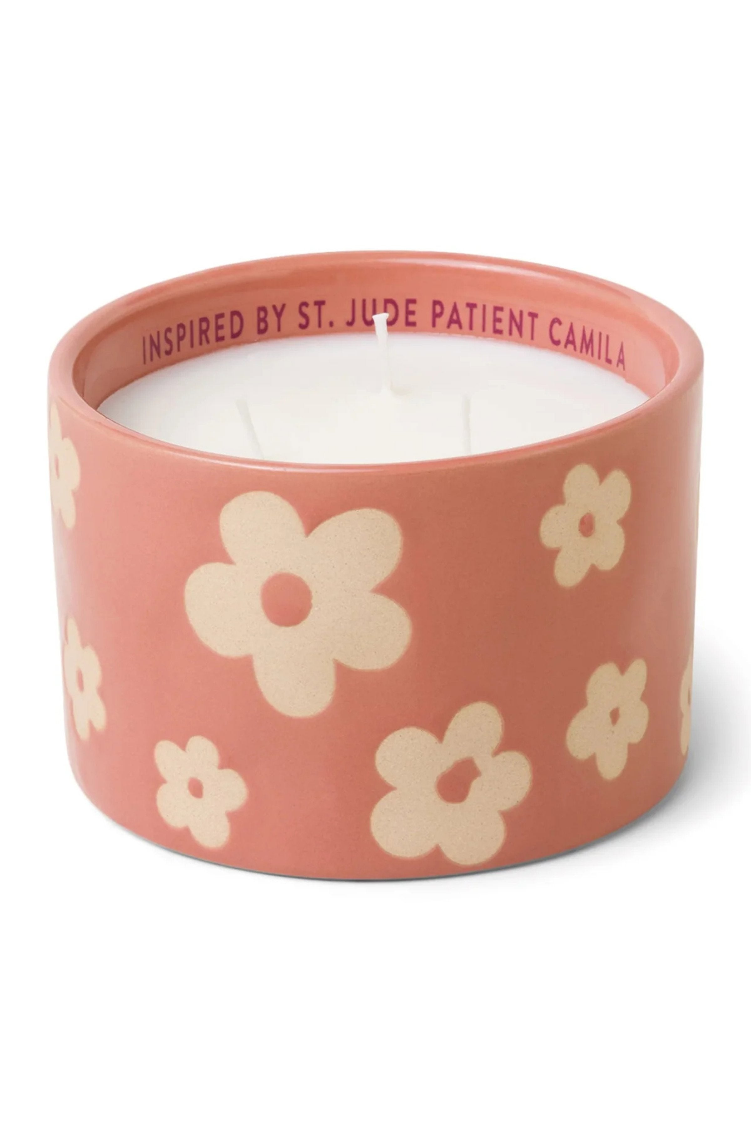 Candle in a pink container with floral designs on a white background