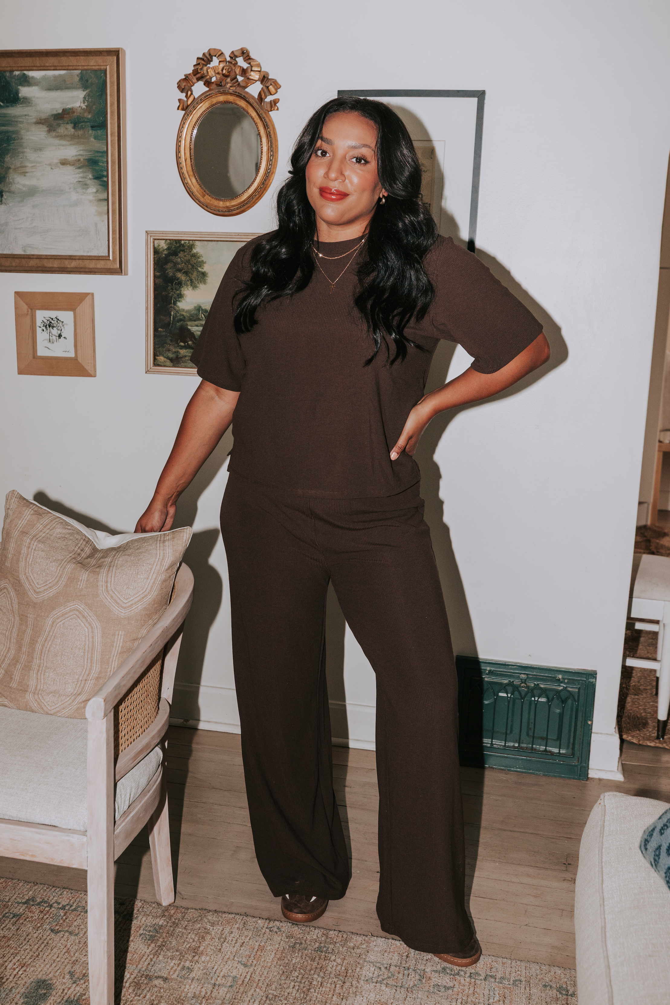 Woman in a brown outfit standing in a living room with decorative elements.