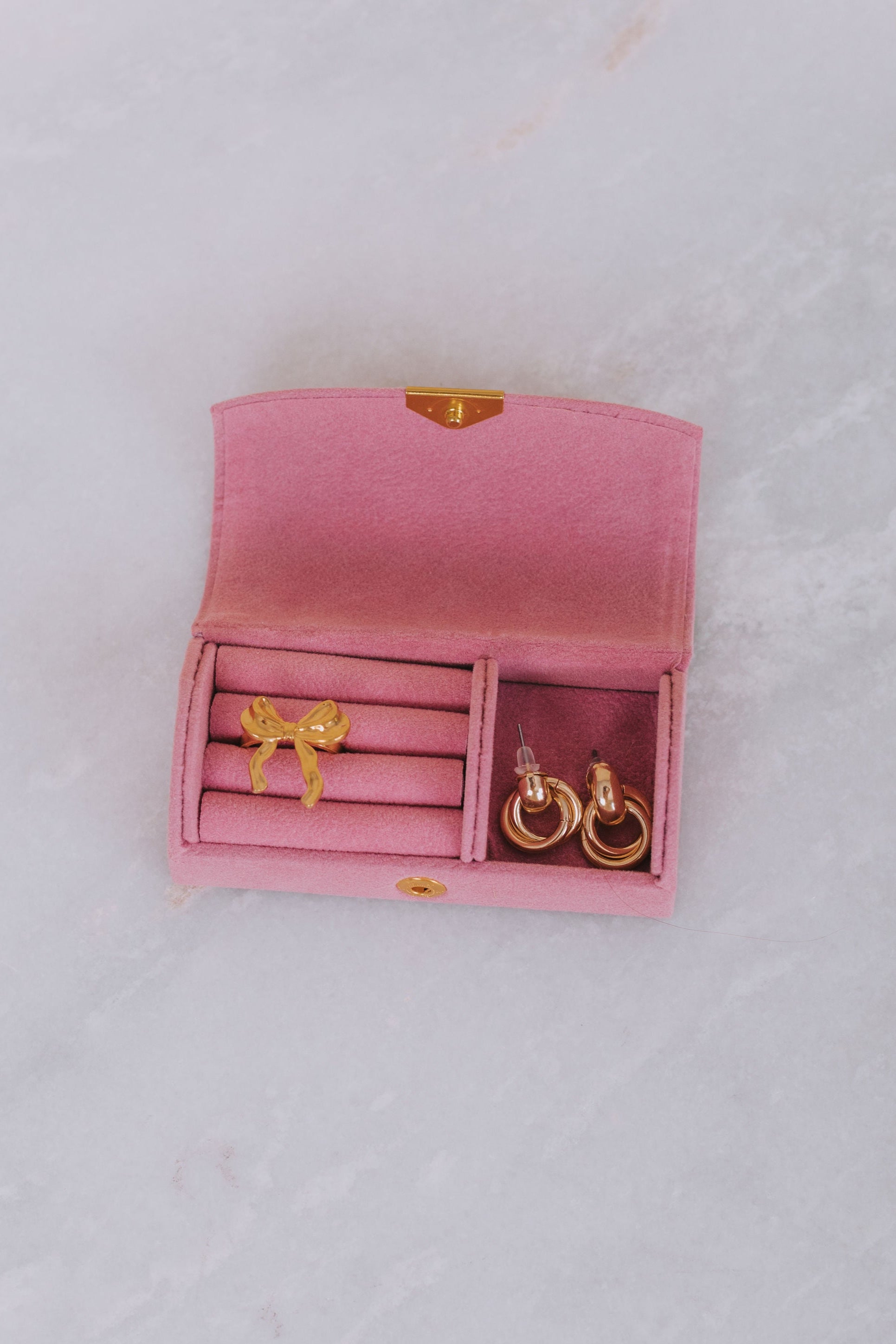 Pink jewelry box with gold earrings on a light gray background