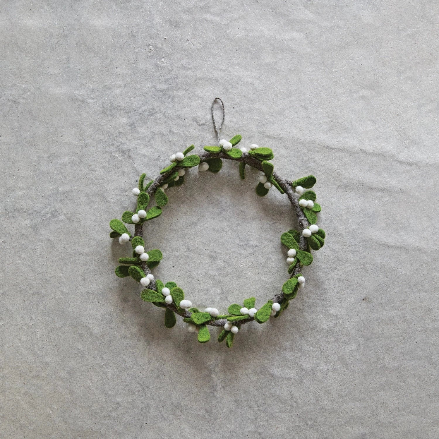 Small green wreath with white berries on a gray background