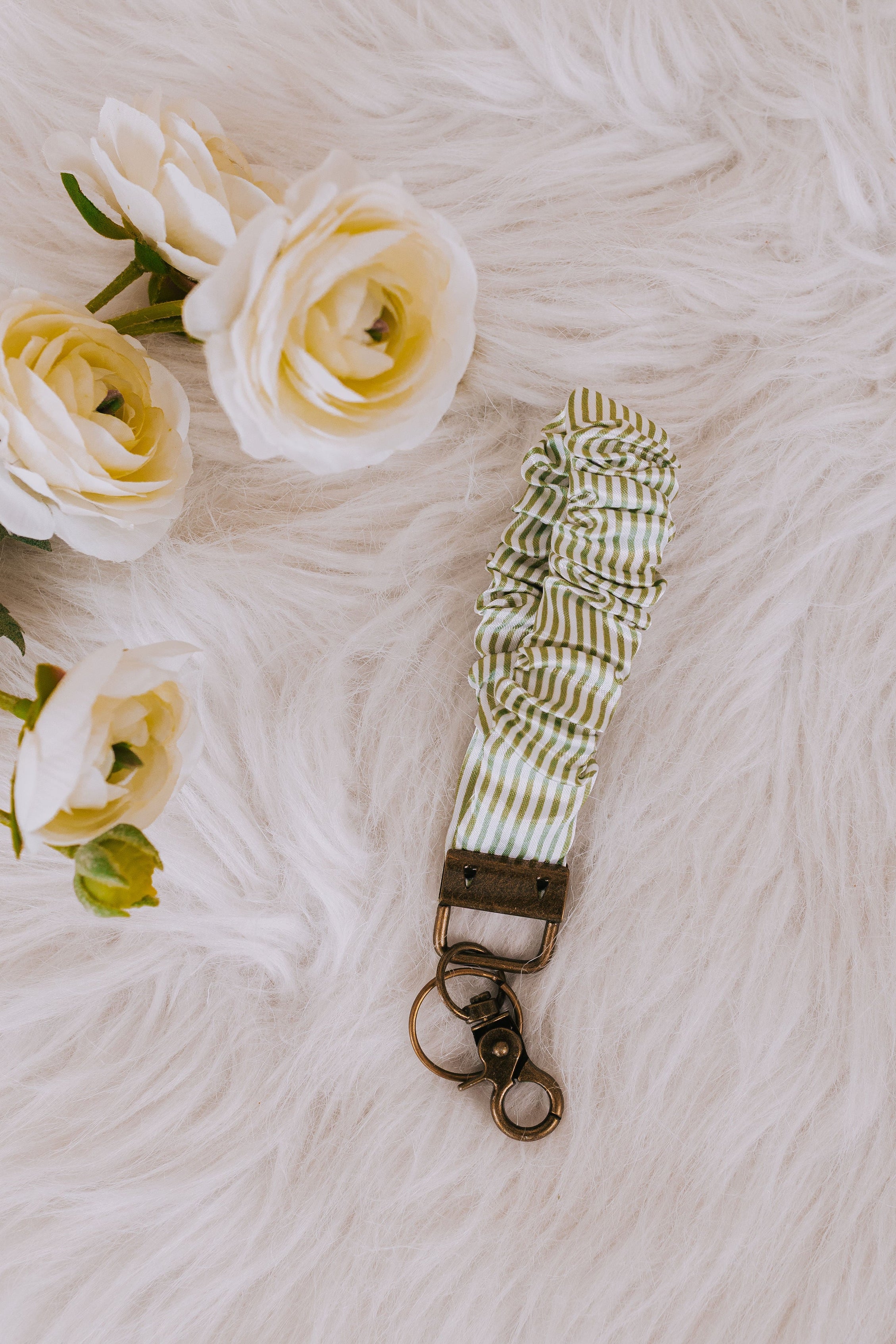 Keychain with striped strap on a textured surface with flowers