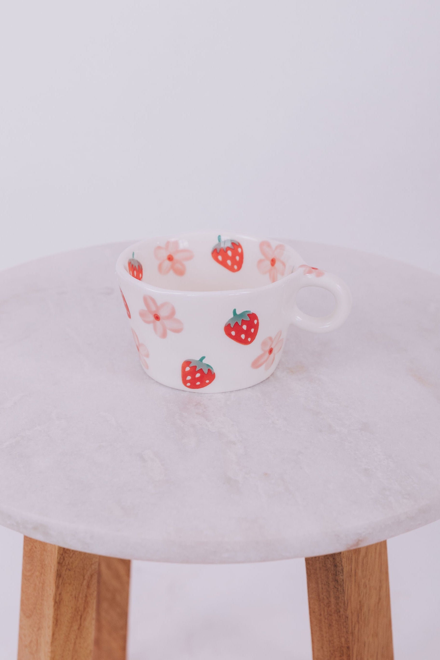 Ceramic mug with strawberry and flower pattern with a white background