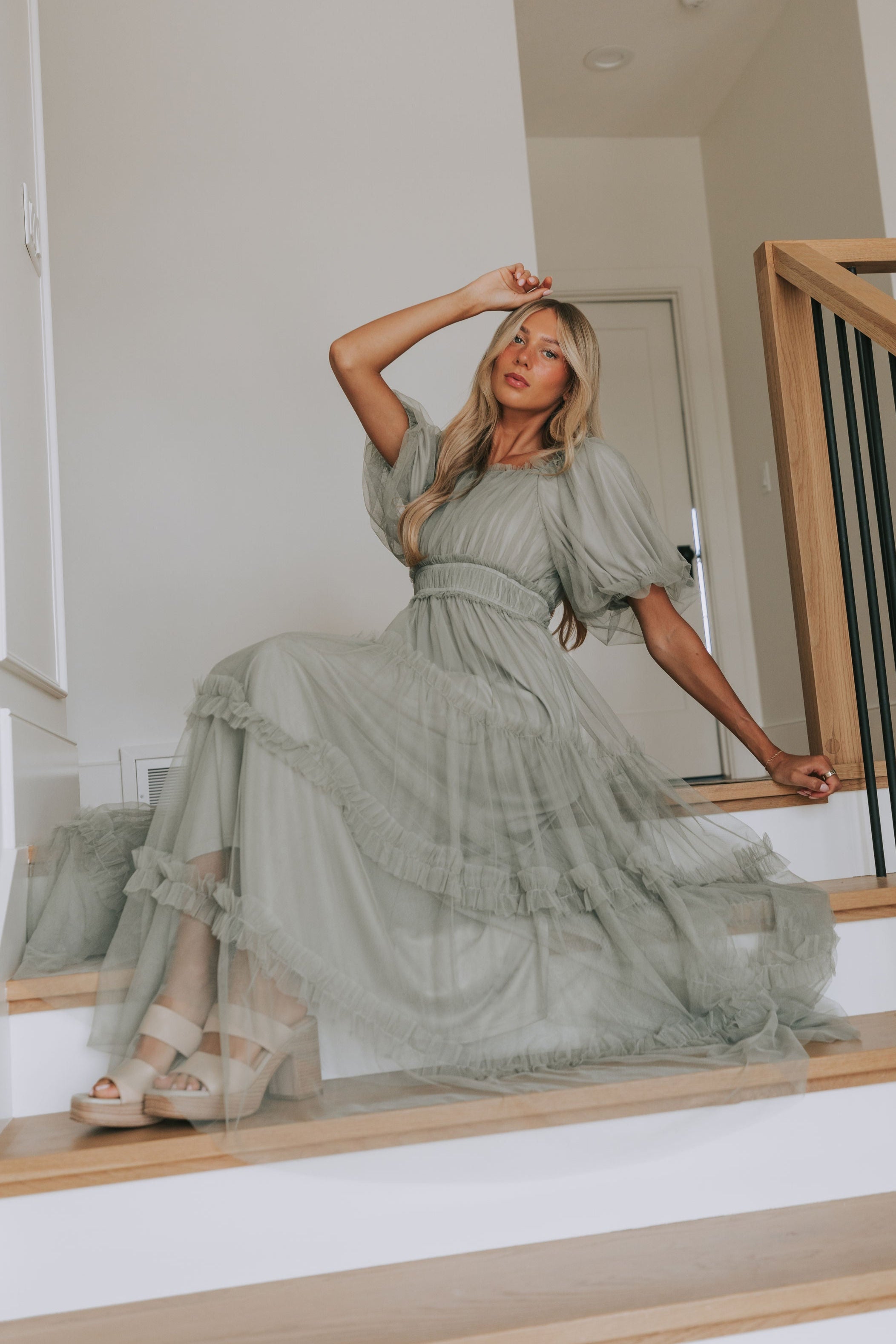 Woman in a green dress sitting on a staircase indoors