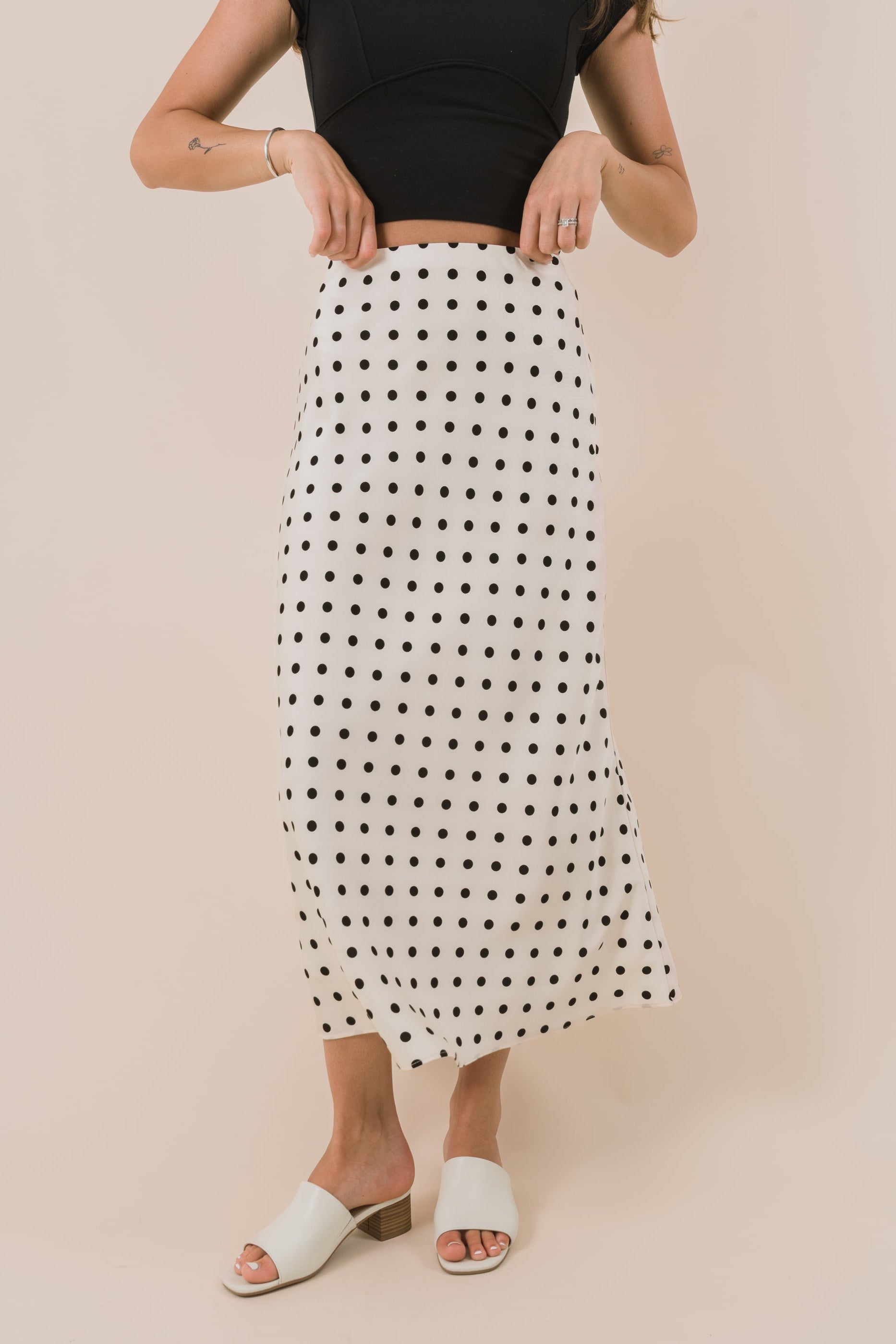 Woman wearing a black and white polka dot skirt on a beige background