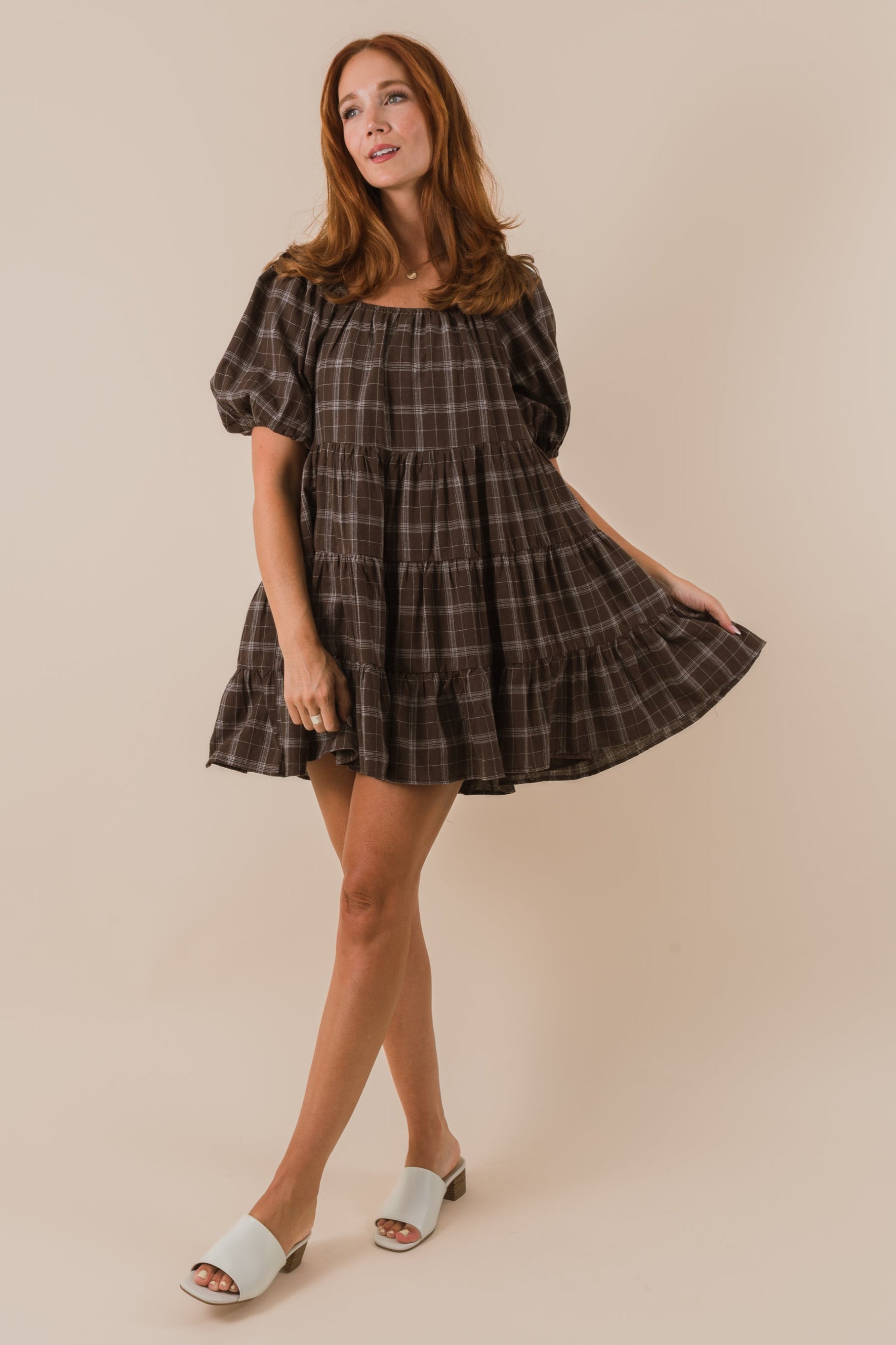 Woman wearing a plaid dress against a beige background