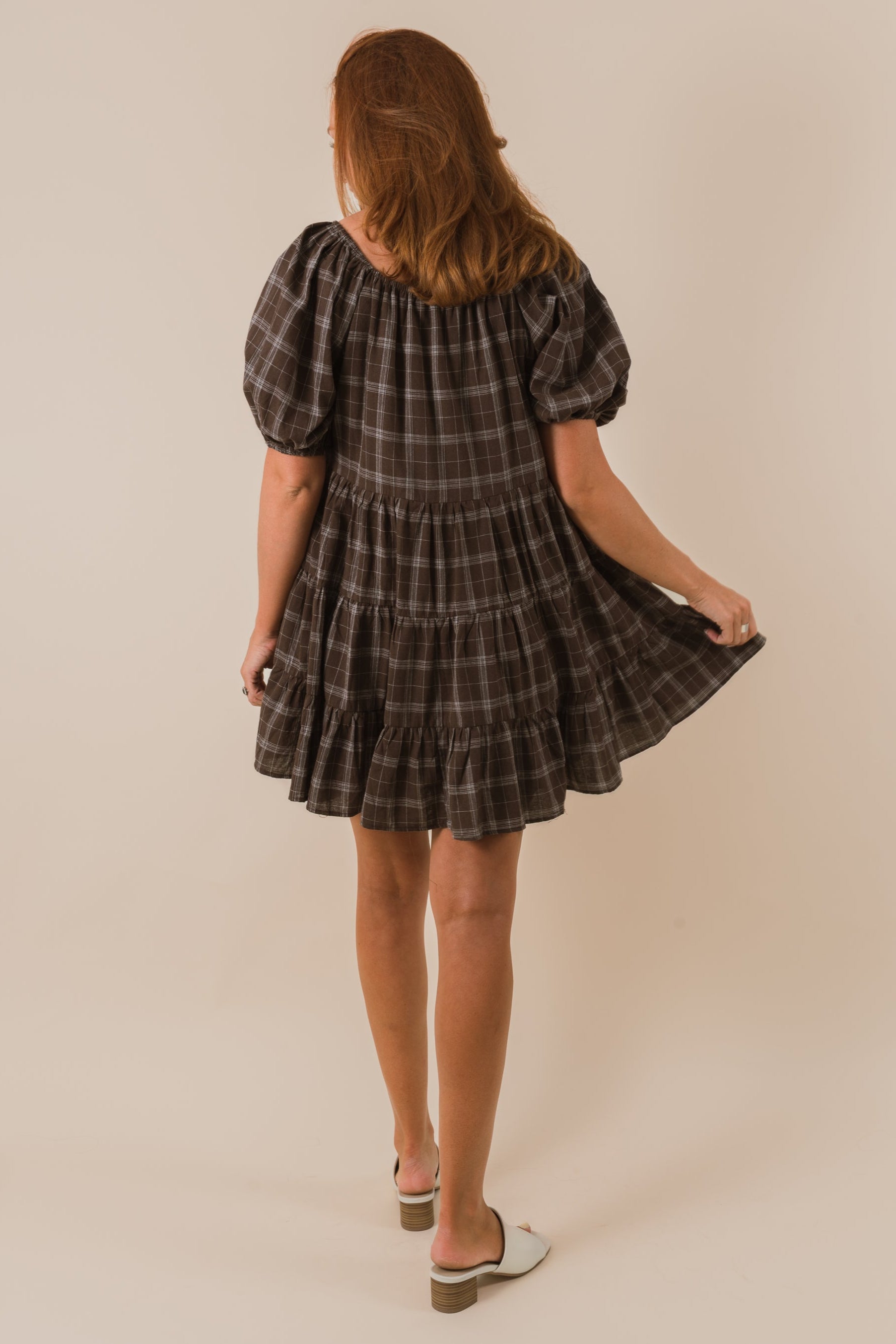 Woman wearing a plaid dress against a plain background