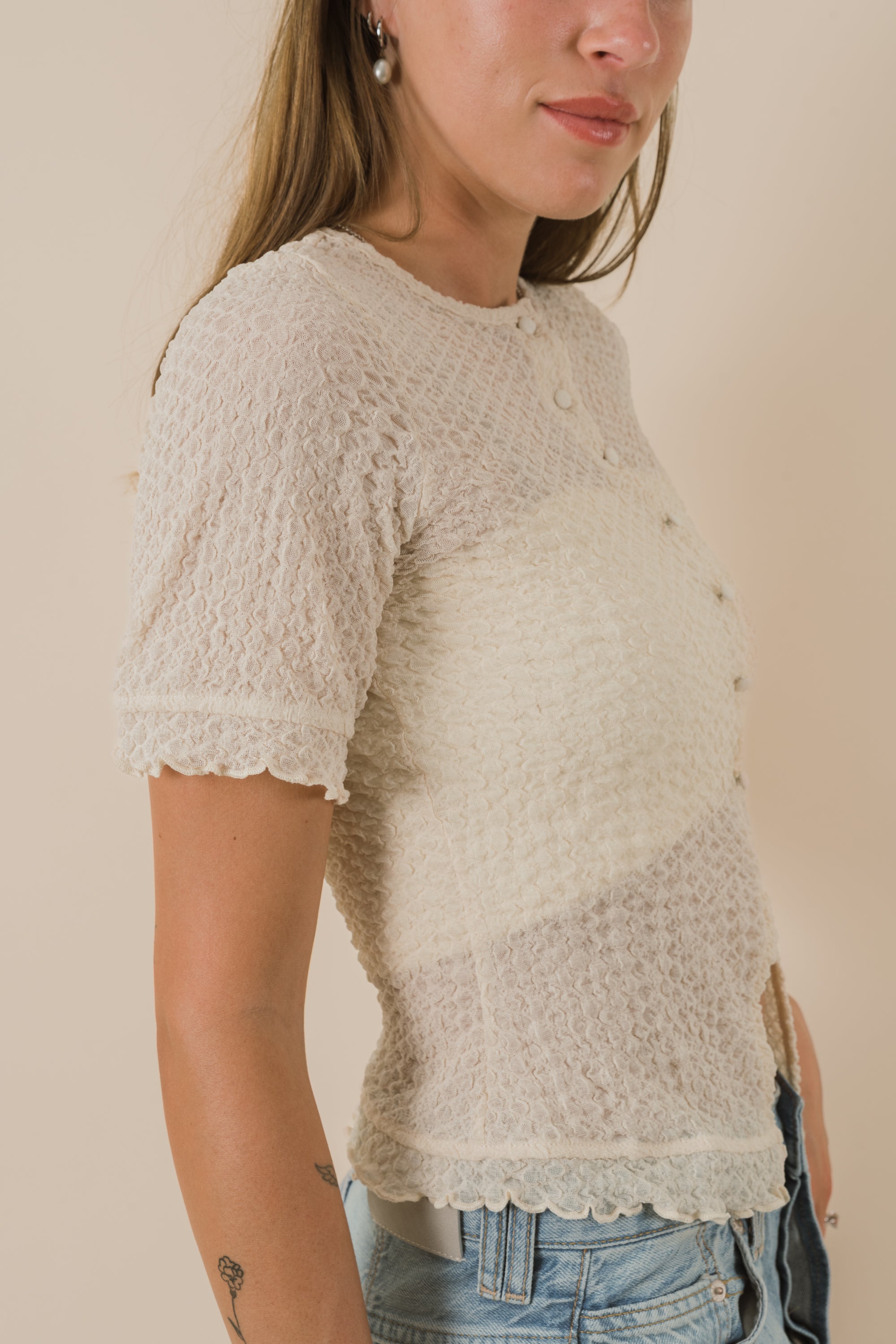 Woman wearing a beige textured top with a plain background