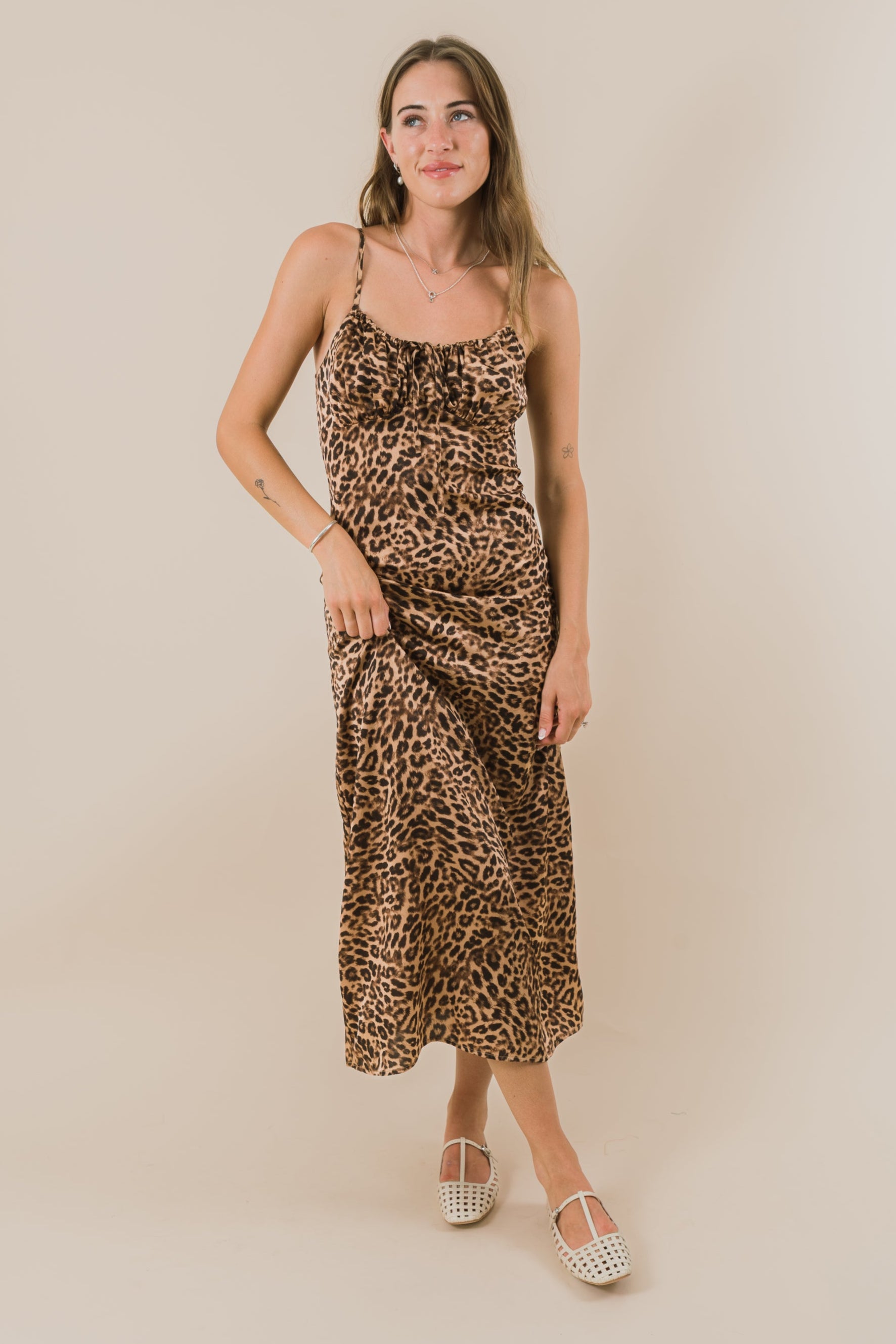 Woman wearing a leopard print dress against a beige background