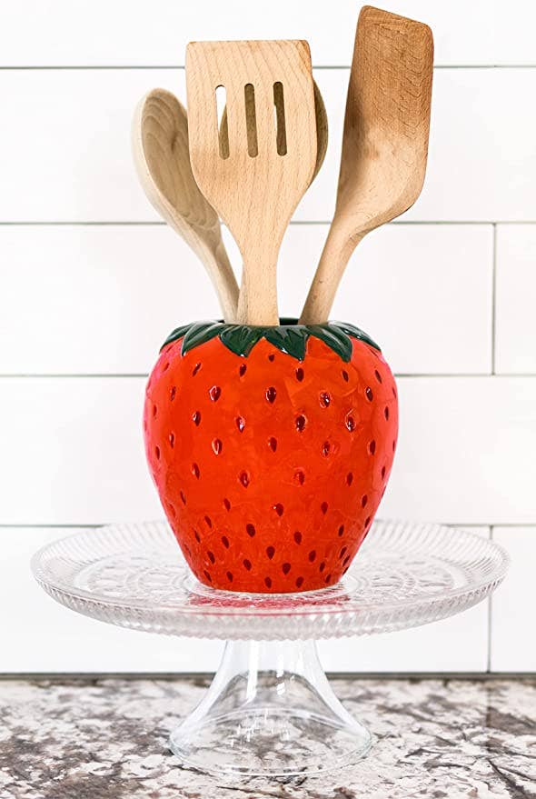 red strawberry vase holding kitchen utensils 