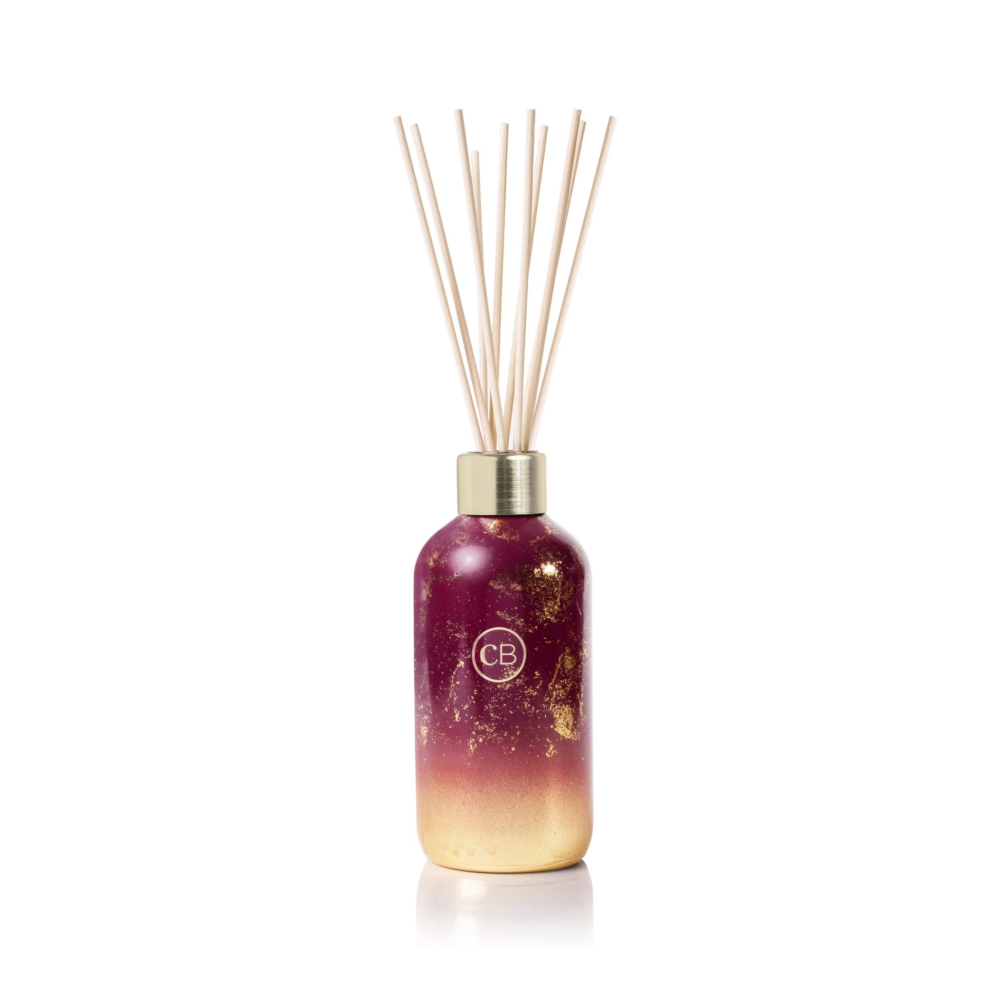 Reed diffuser in tinsel and spice scent with red and gold gradient bottle.