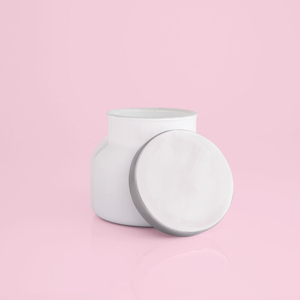White cylindrical container with a circular lid on a pink background