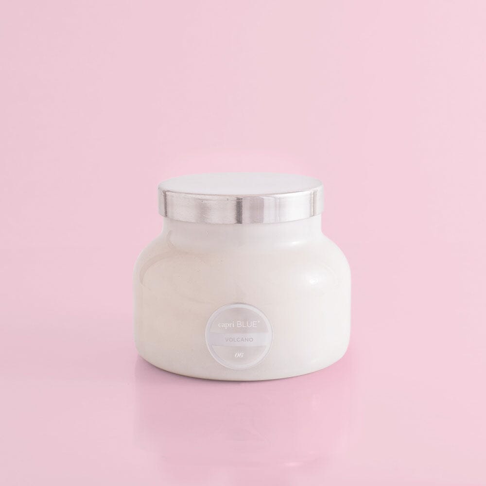 White candle jar with silver lid on a pink background