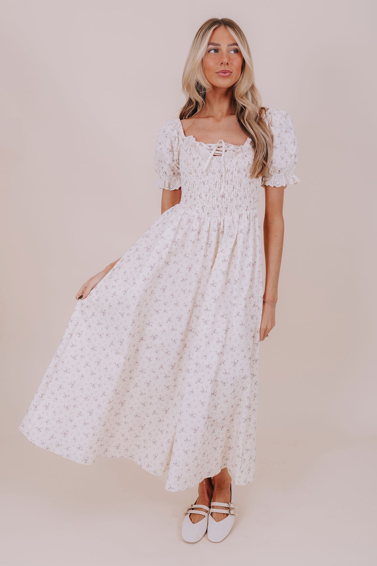 Woman wearing a white floral dress against a beige background