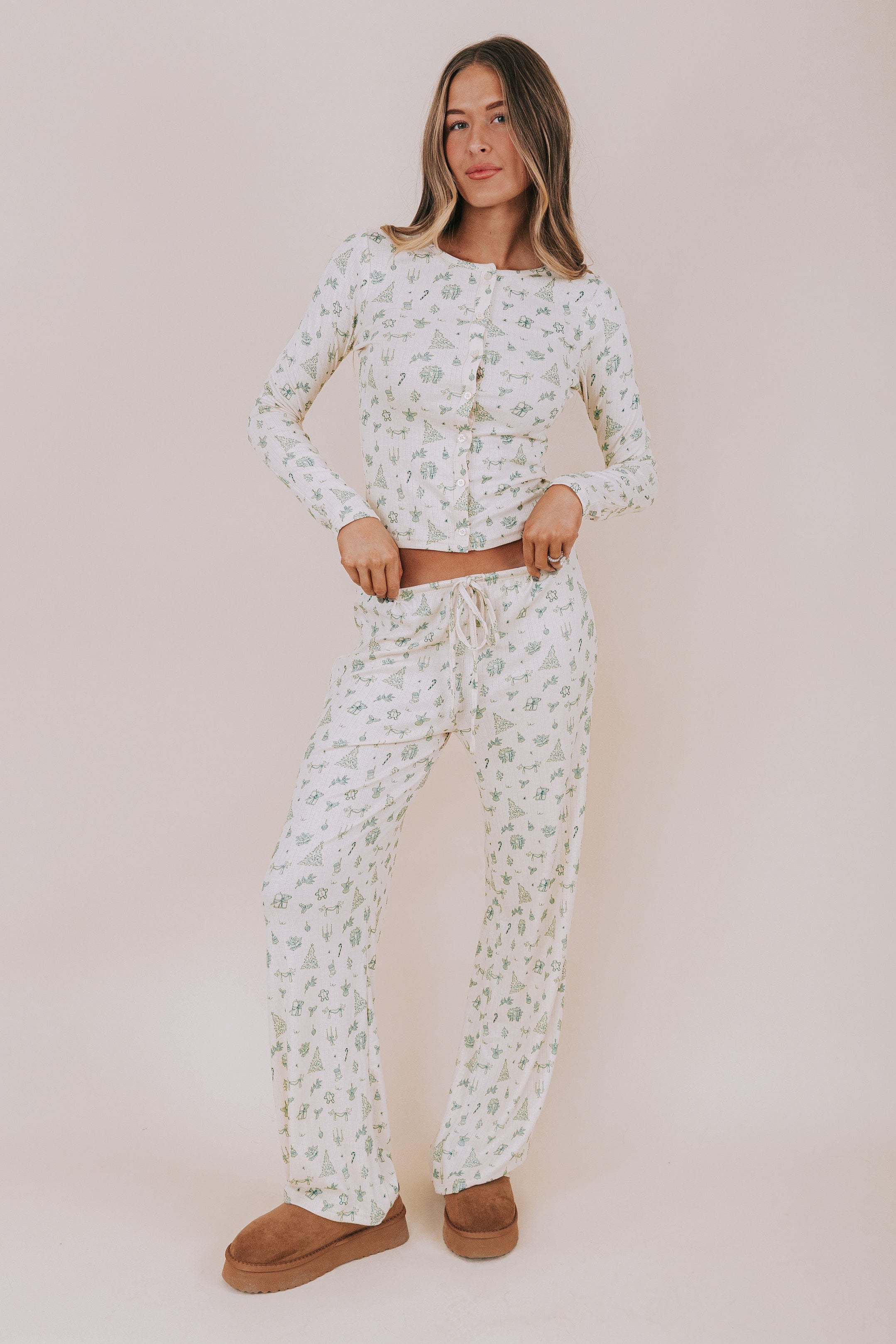 Woman wearing a christmas patterned pajama set against a plain background