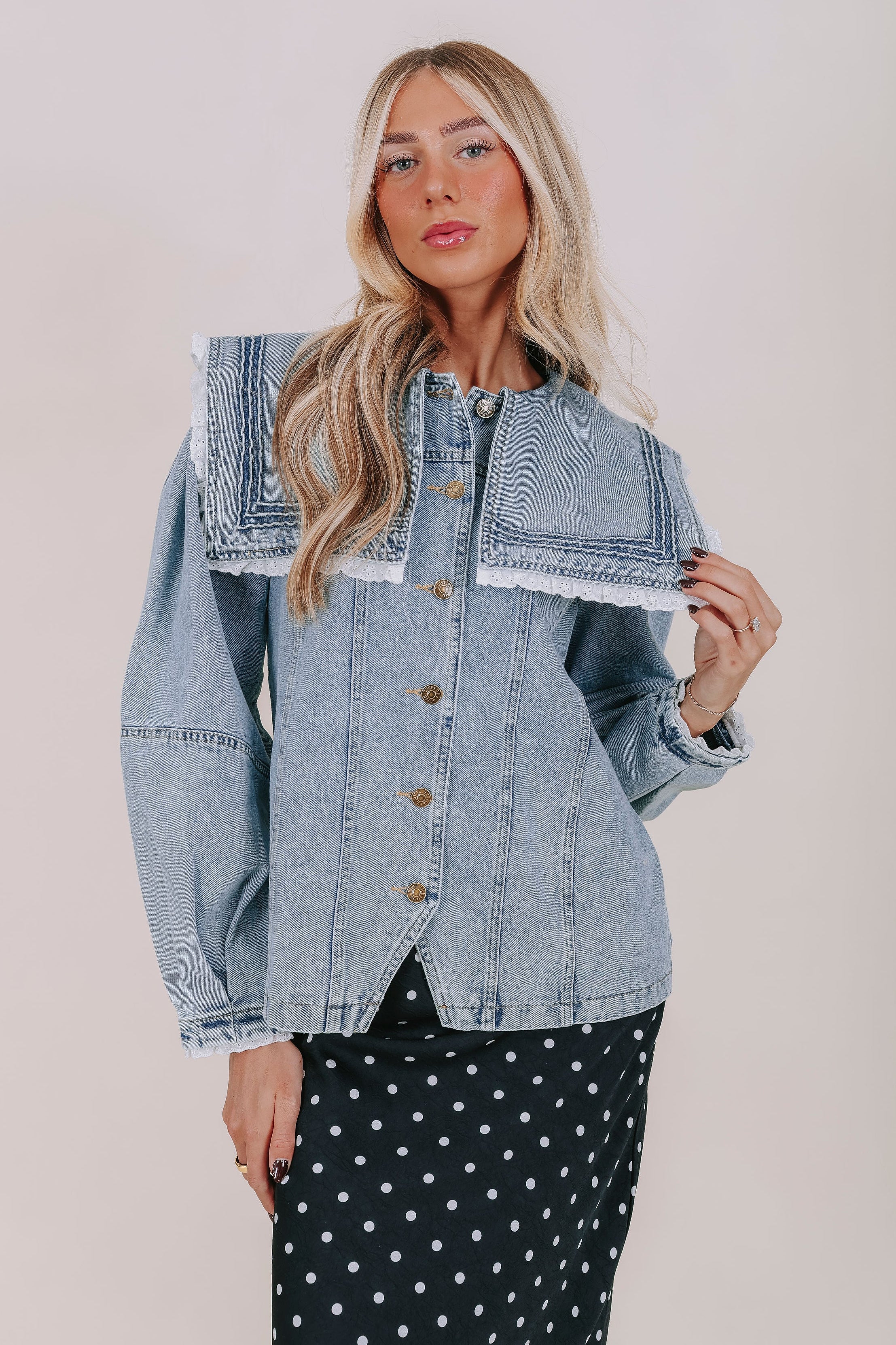 Woman wearing a denim jacket with a plain background