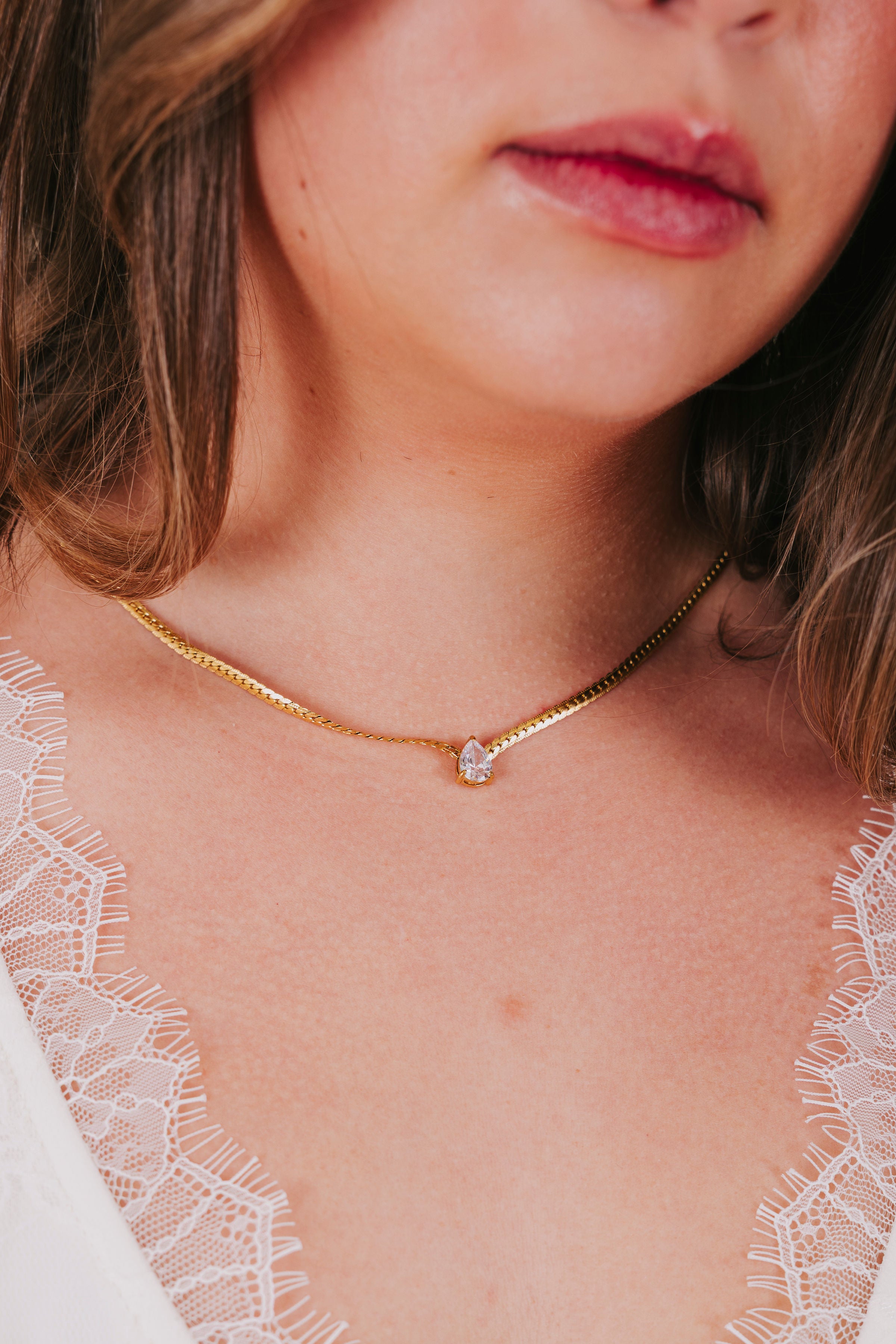 Gold necklace with a herringbone chain and cubic zirconia tear drop pendant