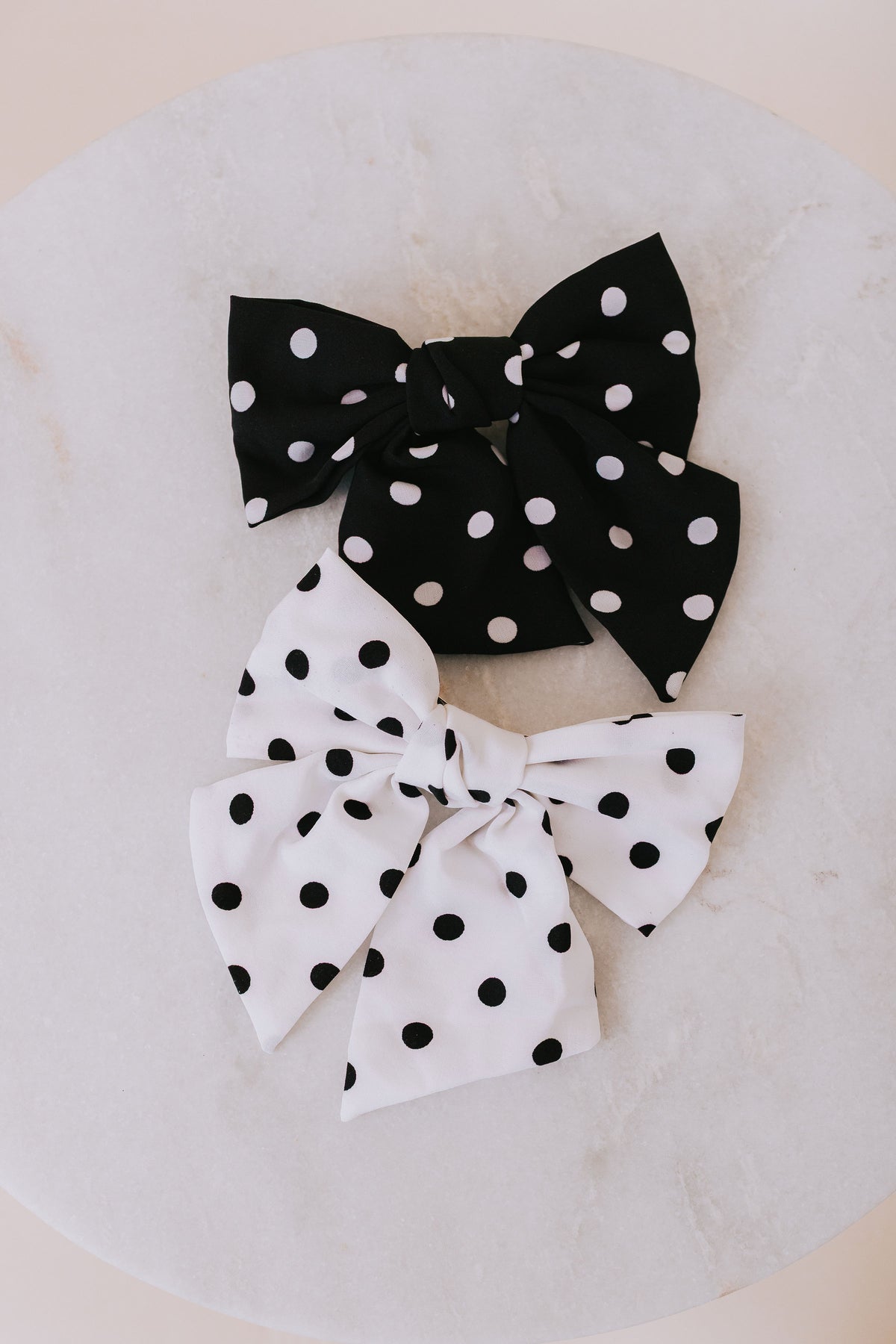 Black and white polka dot hair bows on a neutral background