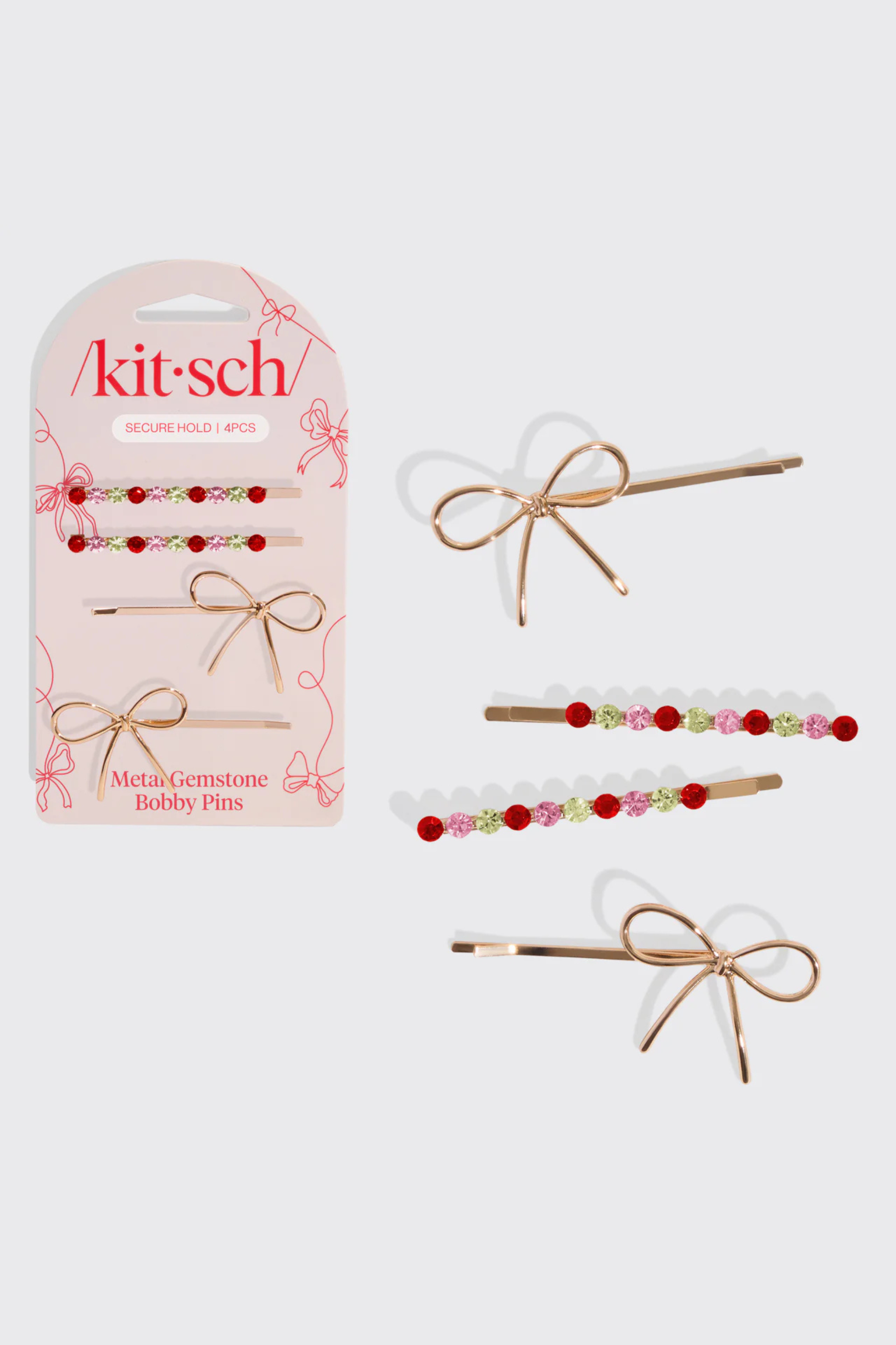 A set of bobby pins in gold with bows and green, pink, and red gemstones.