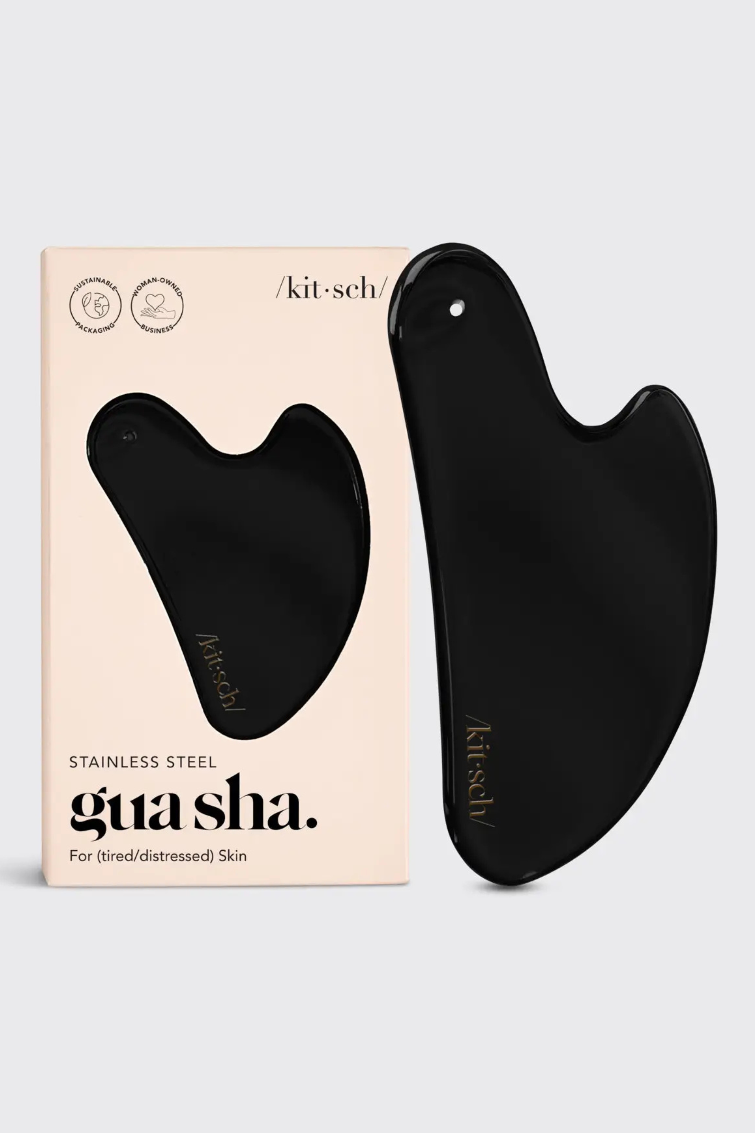 Black gua sha tool with packaging on a light gray background