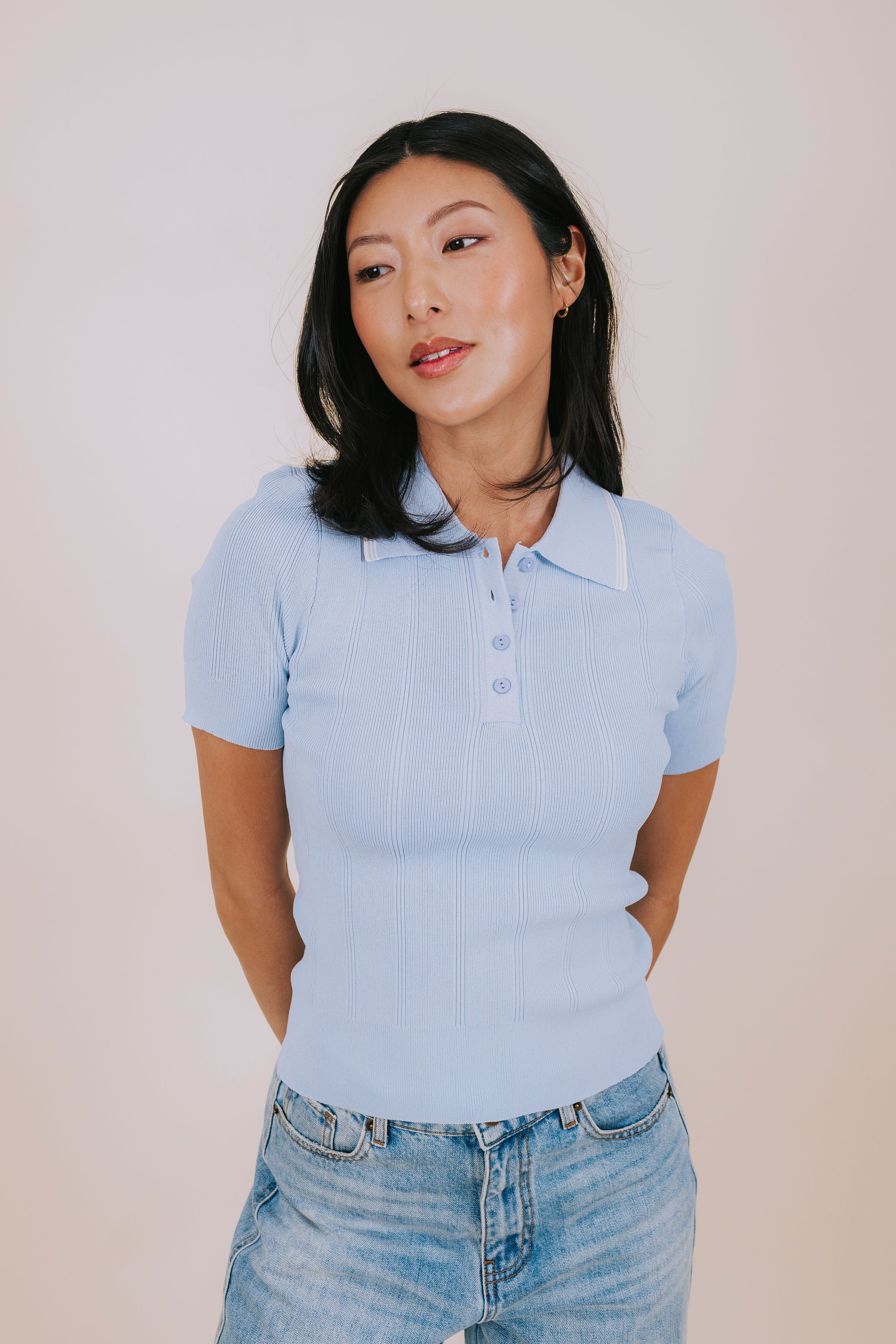Woman wearing a light blue polo shirt with collar, short sleeves, and ribbed material 