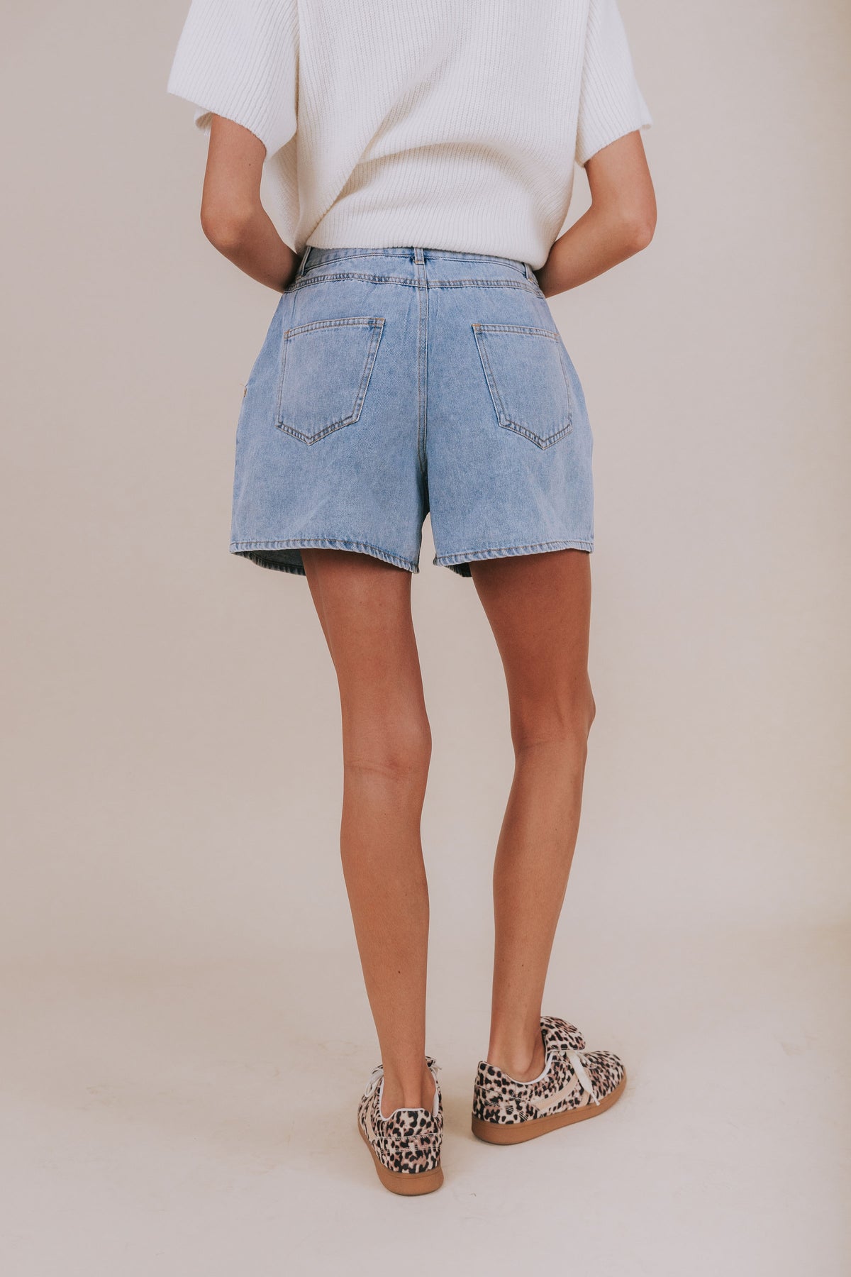 Light wash jean shorts that reach upper-thigh length and have belt loops.