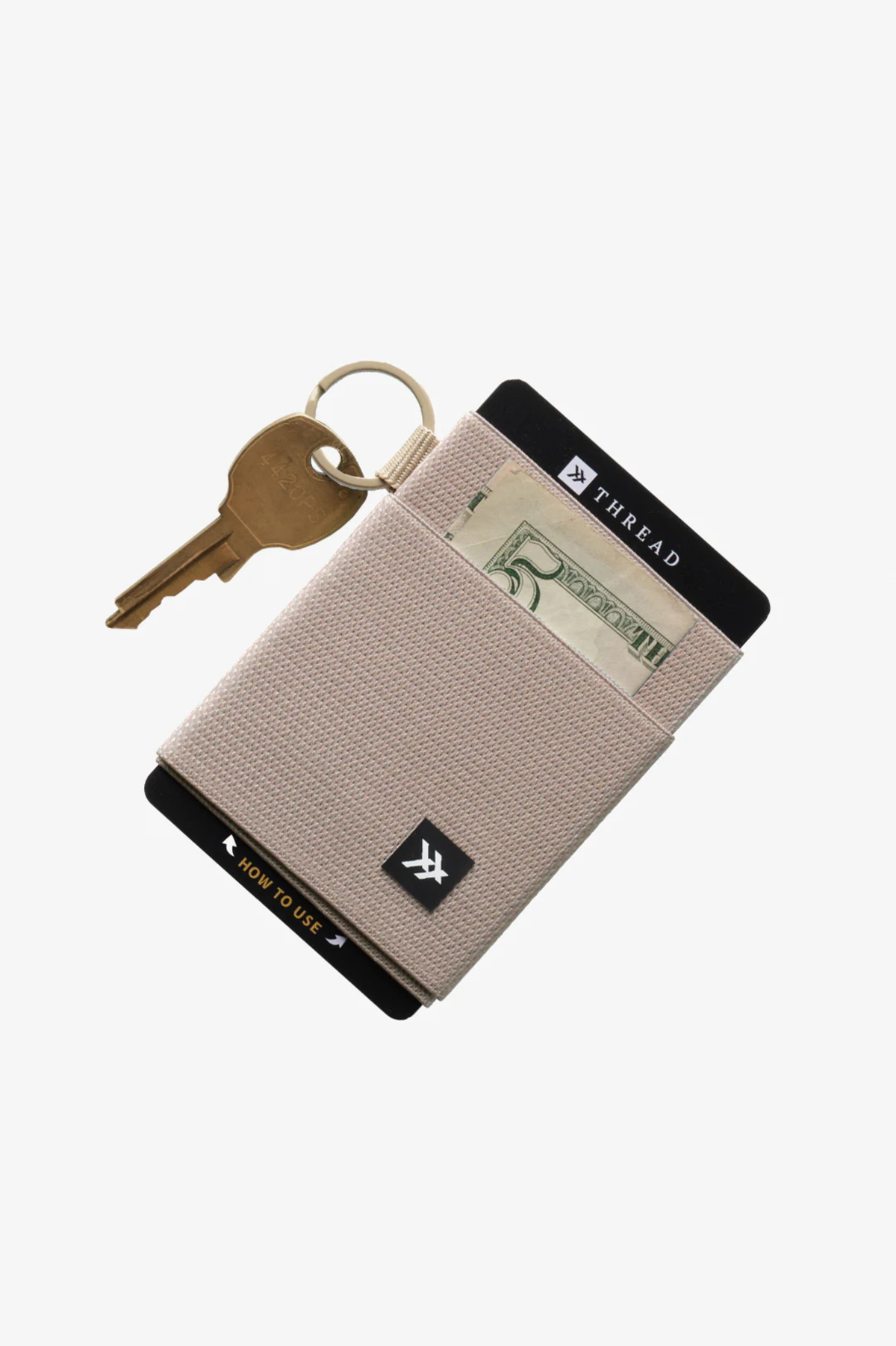 Thread elastic wallet with key ring in sand.