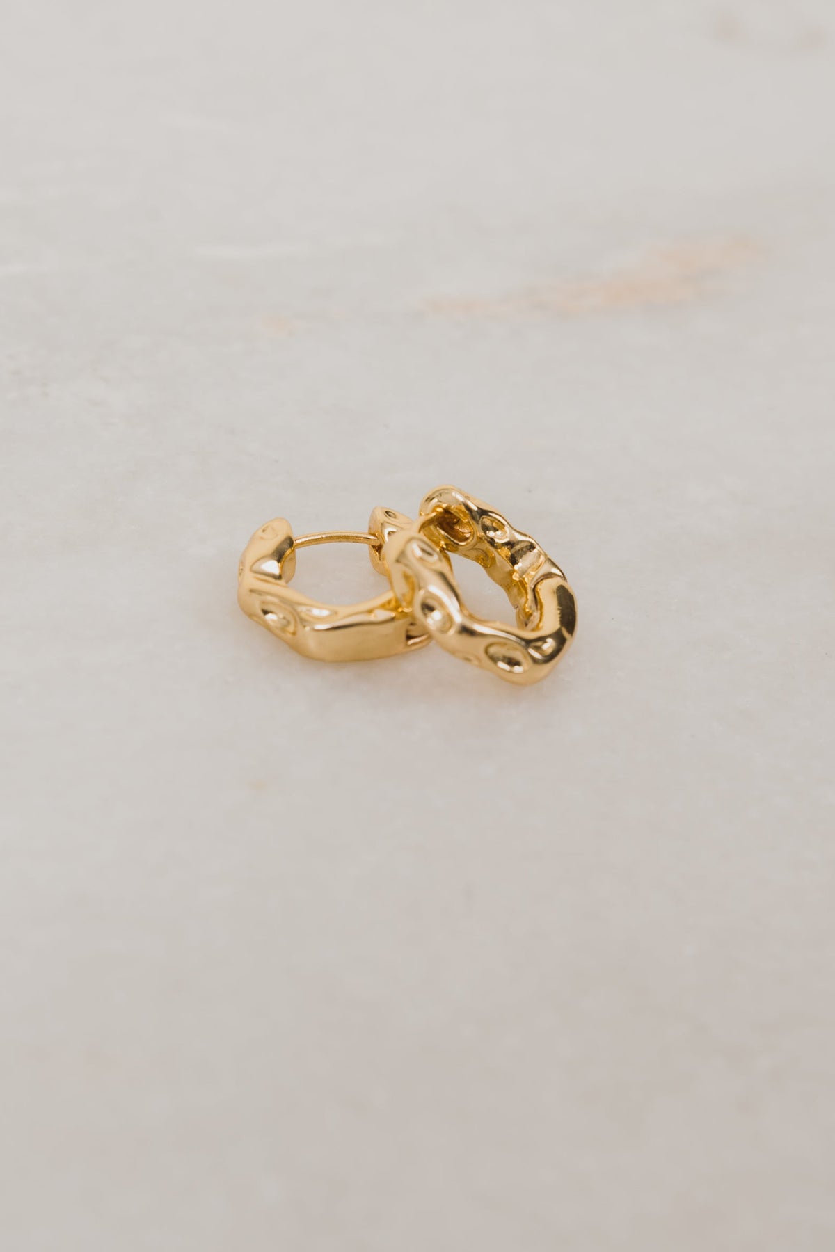 Gold hoop earrings on a light gray background