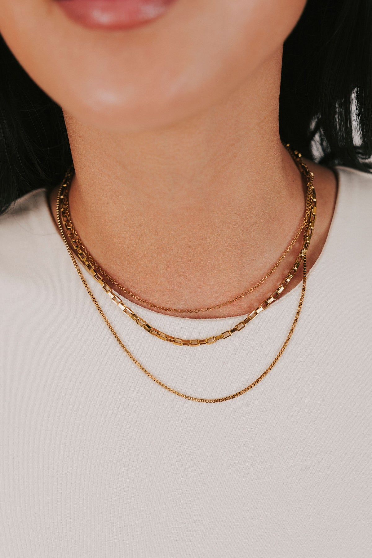 stainless steel gold colored necklace with three layers of box chains and an adjustable lobster clasp 