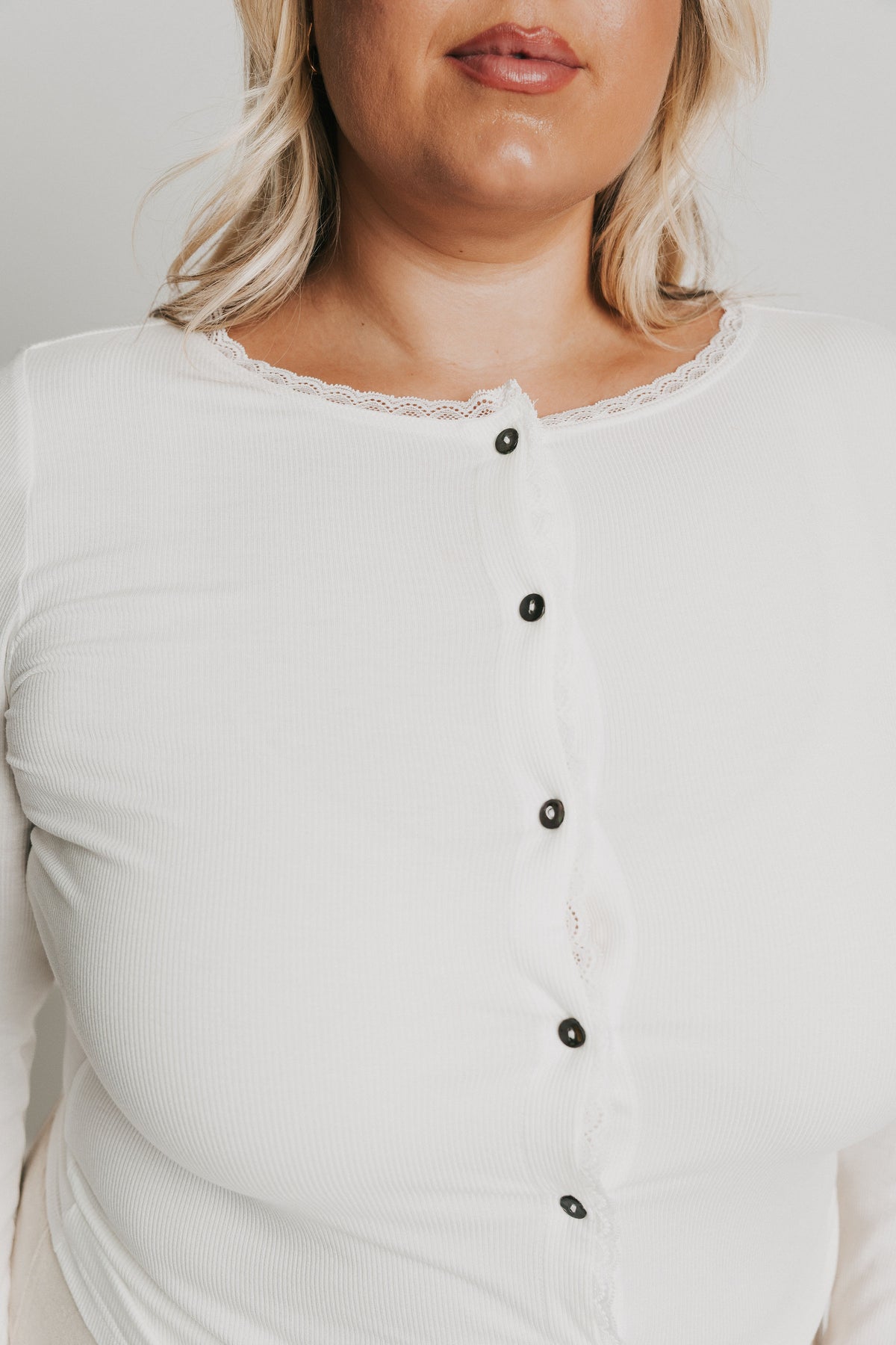 white long sleeve top with buttons and lace trim on neckline 