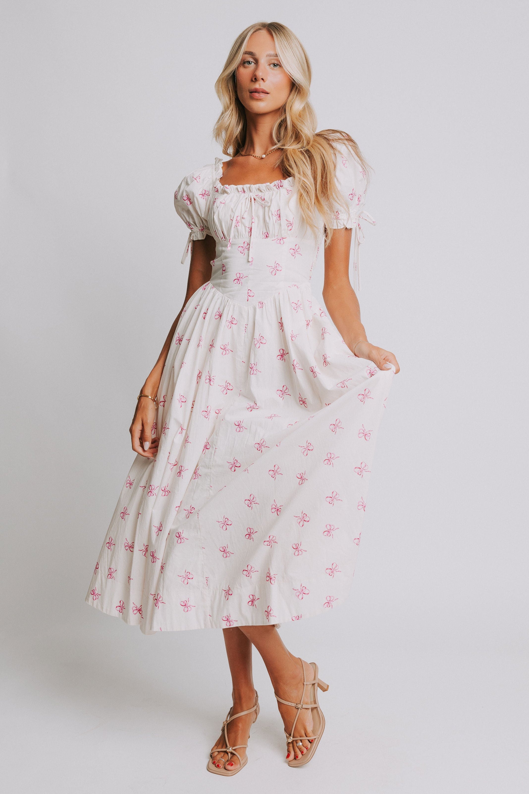 white midi dress with pink bow print and ruched bust and puff sleeves