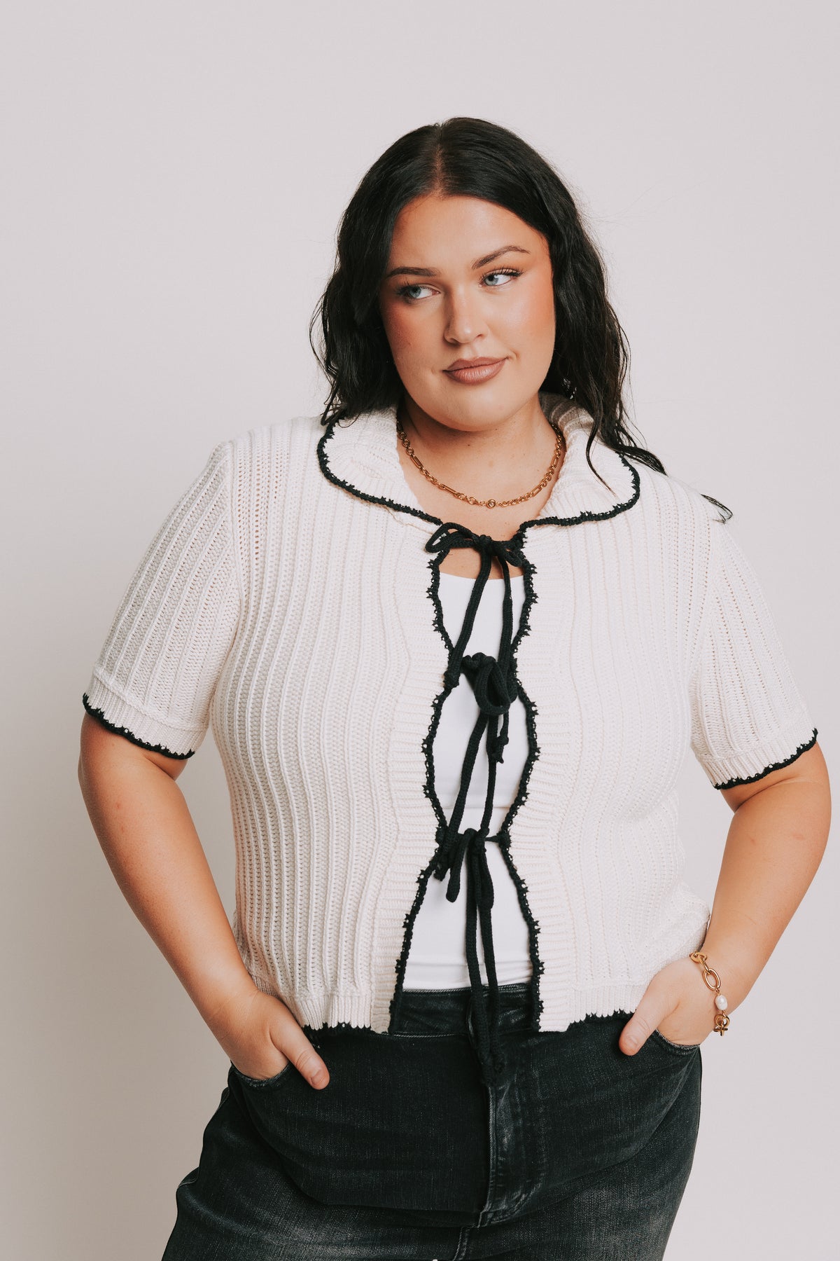 white sweater top with black bows down the front and collar 