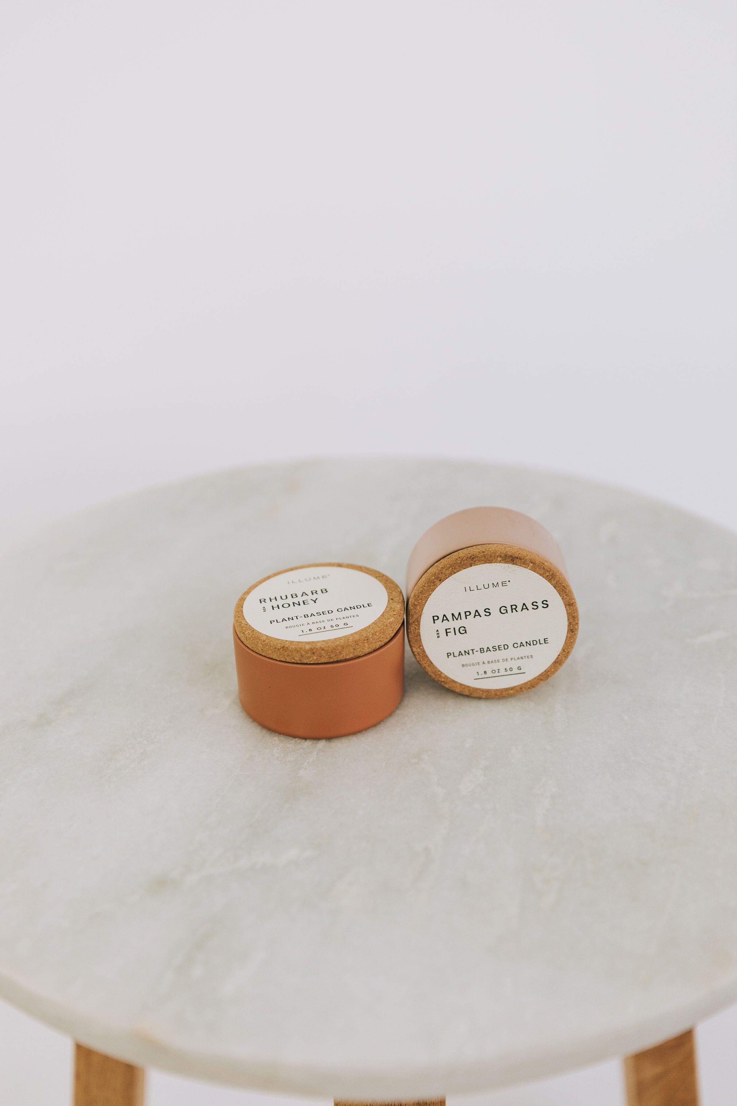 Two small cylindrical candles in pampas grass and fig, or rhubarb and honey.