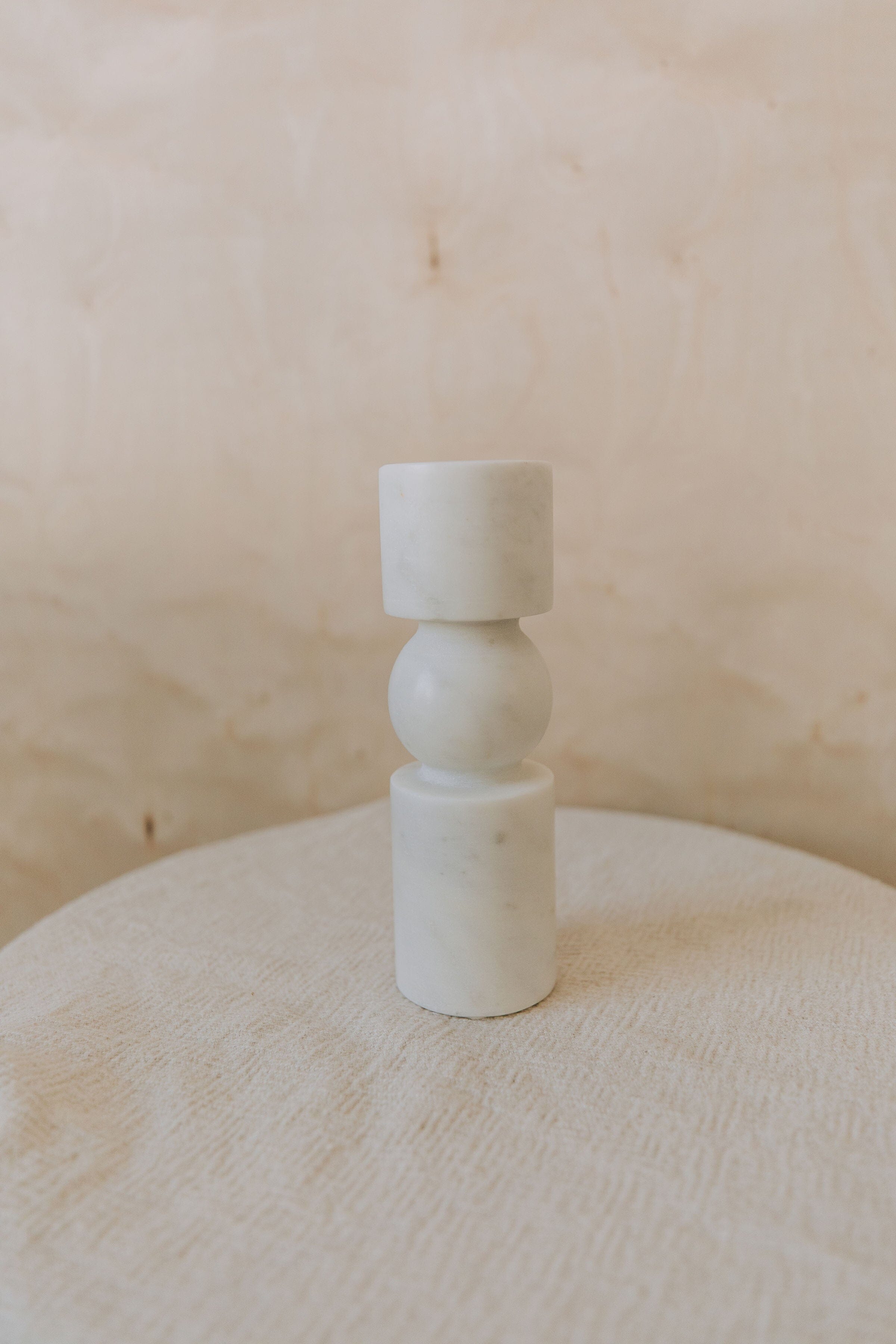 White marble candle holder on a textured surface with a neutral background